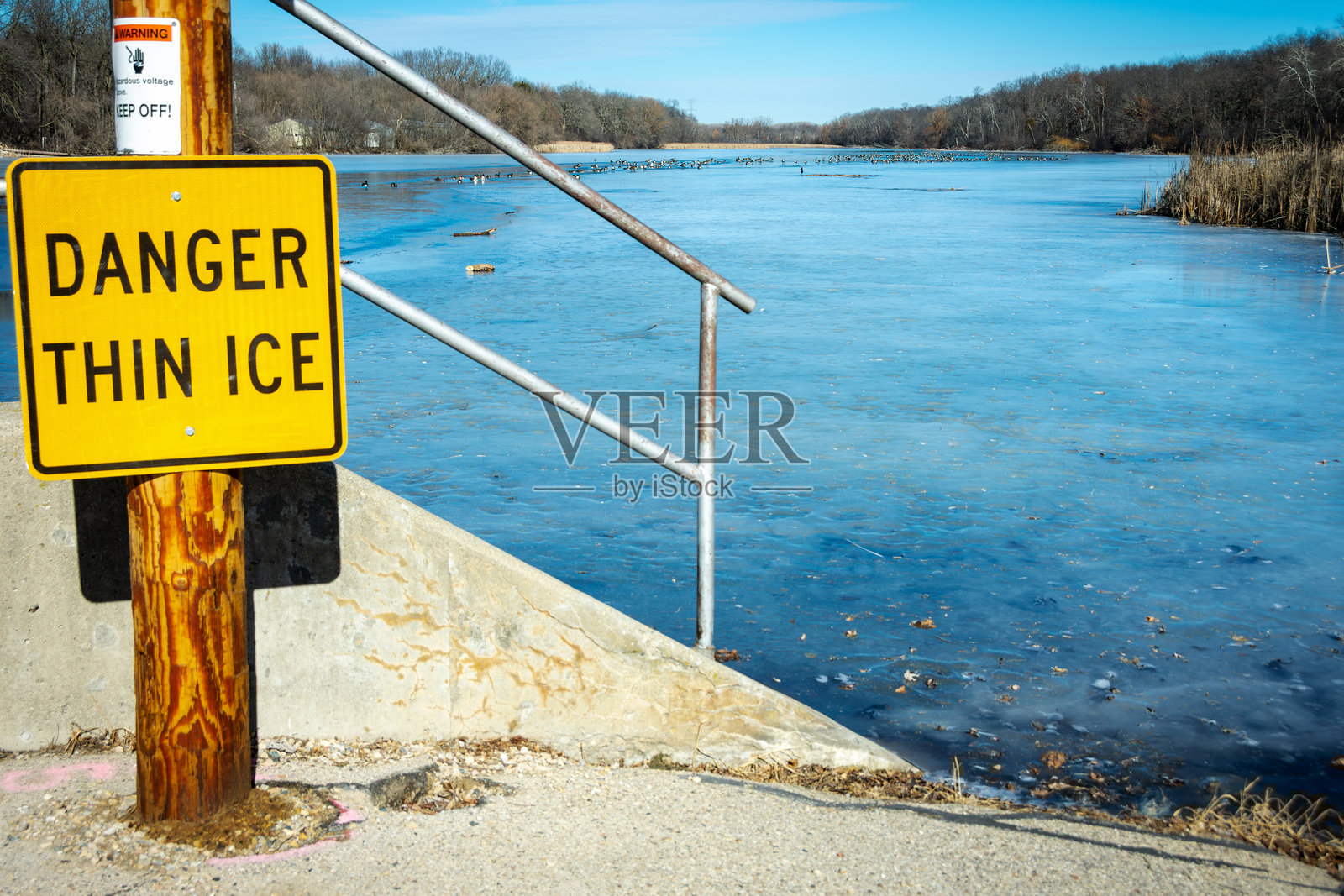 警告标志提示薄冰，背景中可见薄冰。照片摄影图片