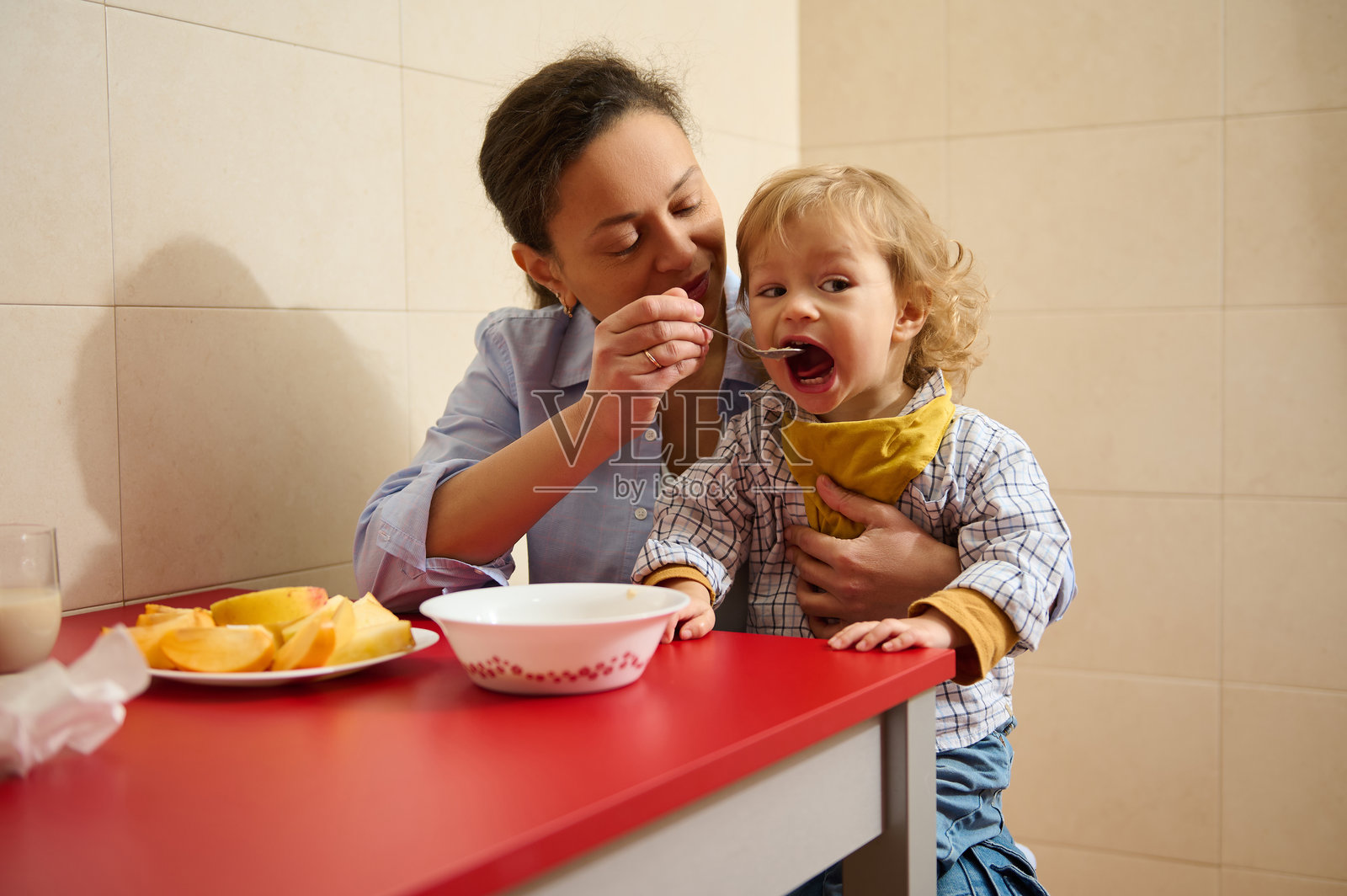 母亲在温馨的室内环境中喂孩子早餐，享受亲密时光照片摄影图片