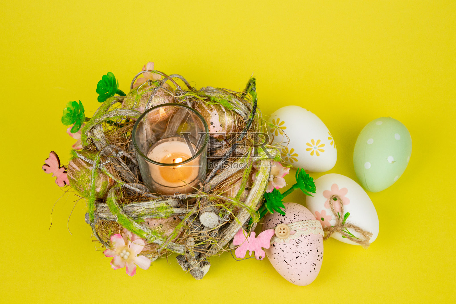 复活节彩蛋和一支蜡烛。黄色背景上的复活节彩色鸡蛋。照片摄影图片