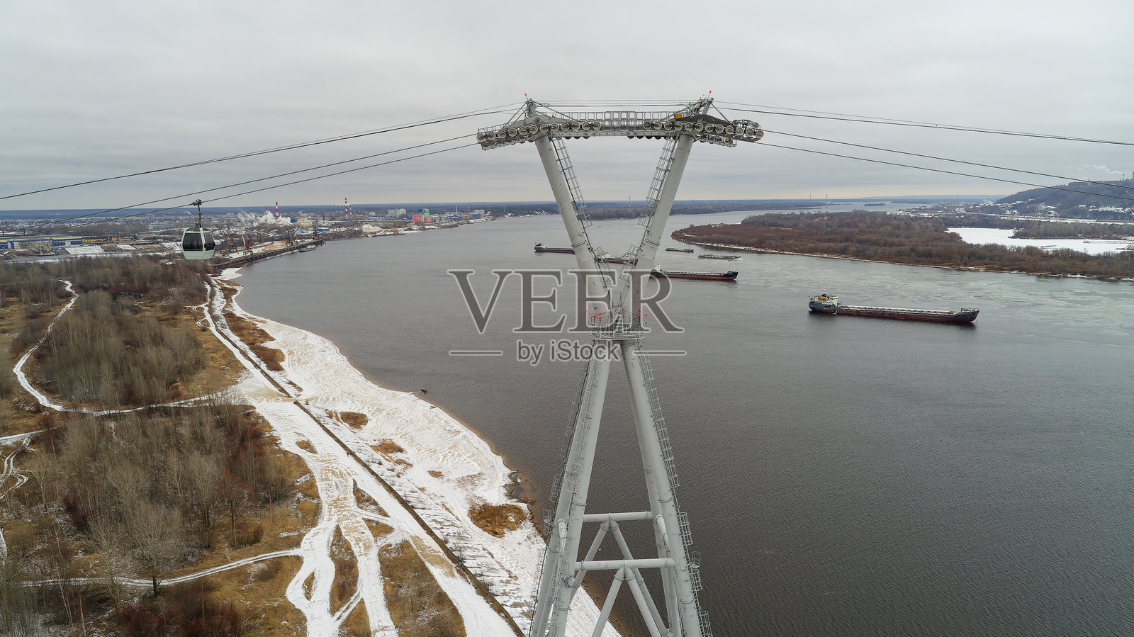 电力塔矗立在水面上方。冰冻的俄罗斯伏尔加河水道。照片摄影图片