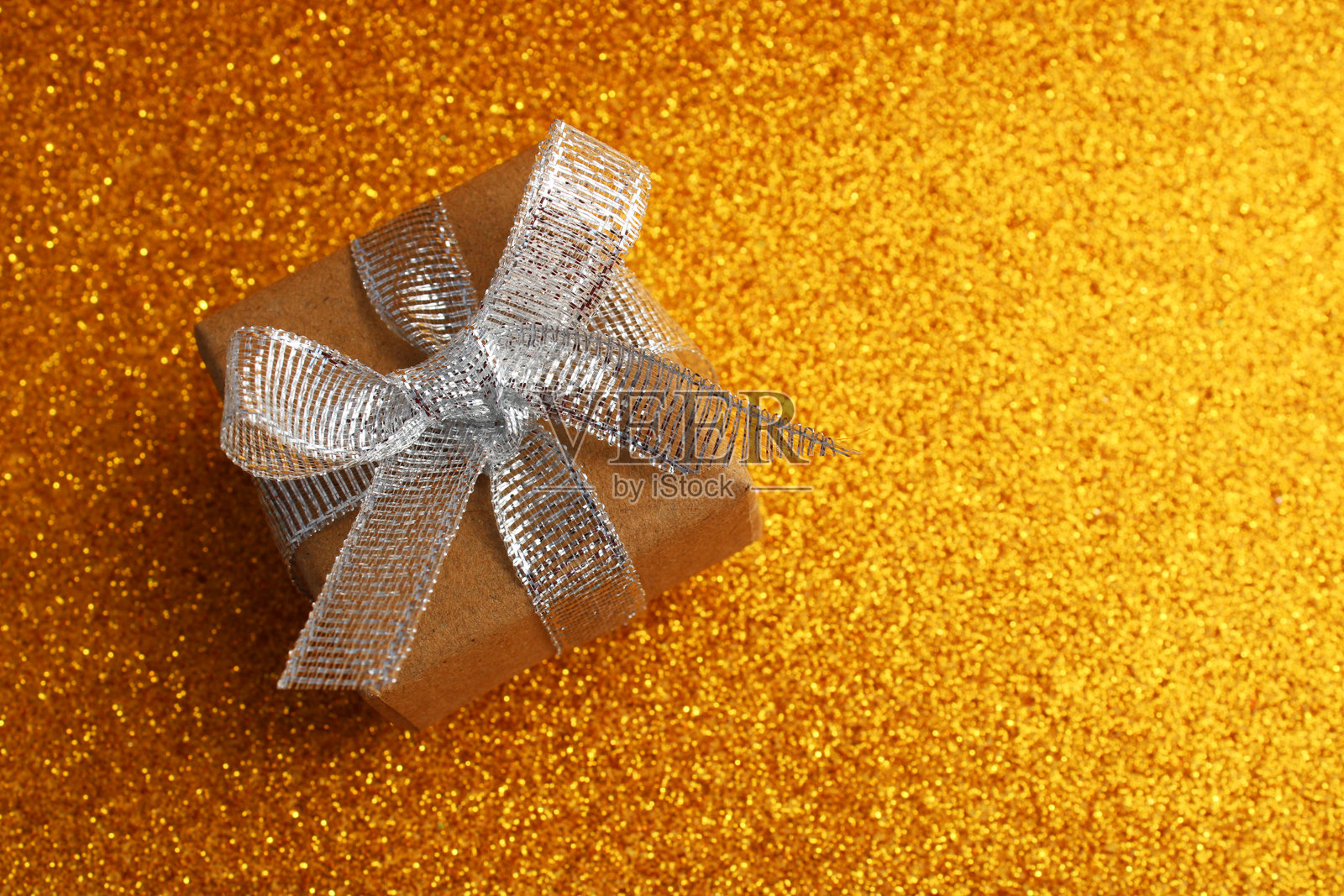 金色背景上的银色闪光丝带蝴蝶结礼品盒照片摄影图片