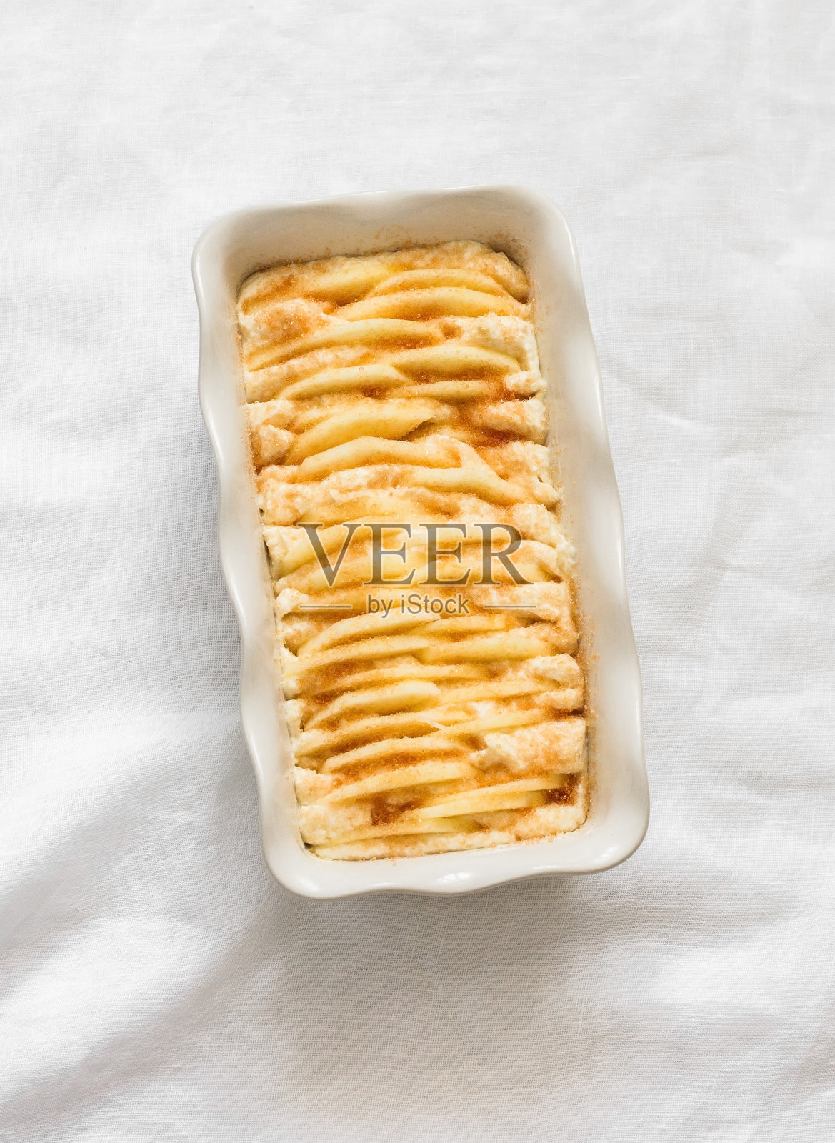 烹饪奶酪苹果肉桂砂锅 - 美味的早餐，轻盈背景上的甜点，俯视图照片摄影图片