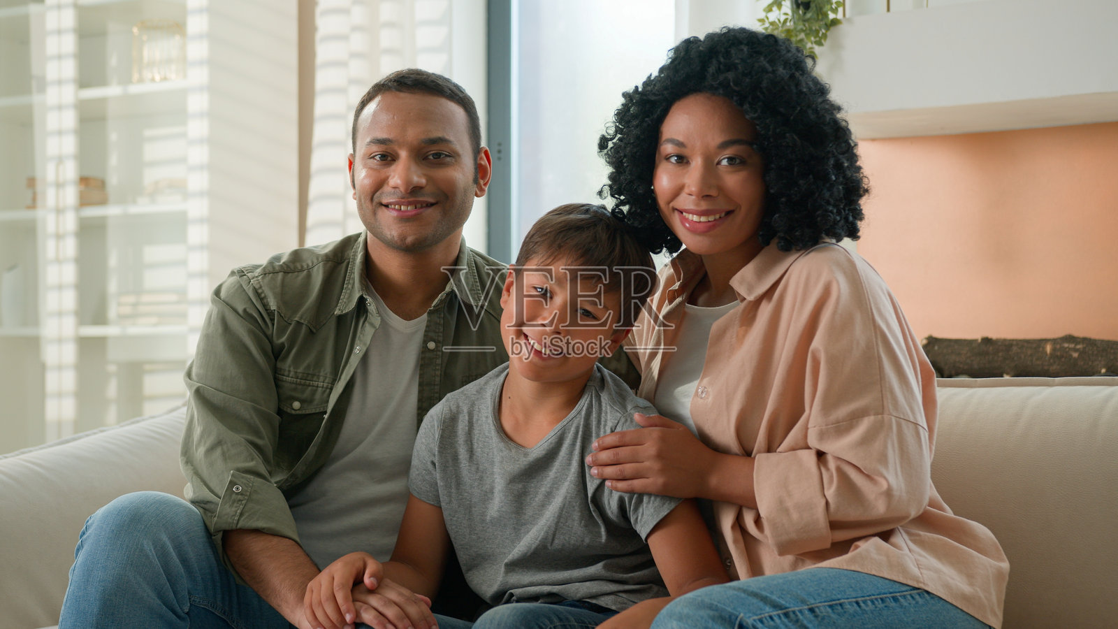 多种族的非裔美国人和白人快乐家庭肖像，父母在家中微笑，父亲和母亲拥抱小男孩，幼儿园孩子坐在沙发上，体现了多元世代的亲子之爱与关怀。照片摄影图片