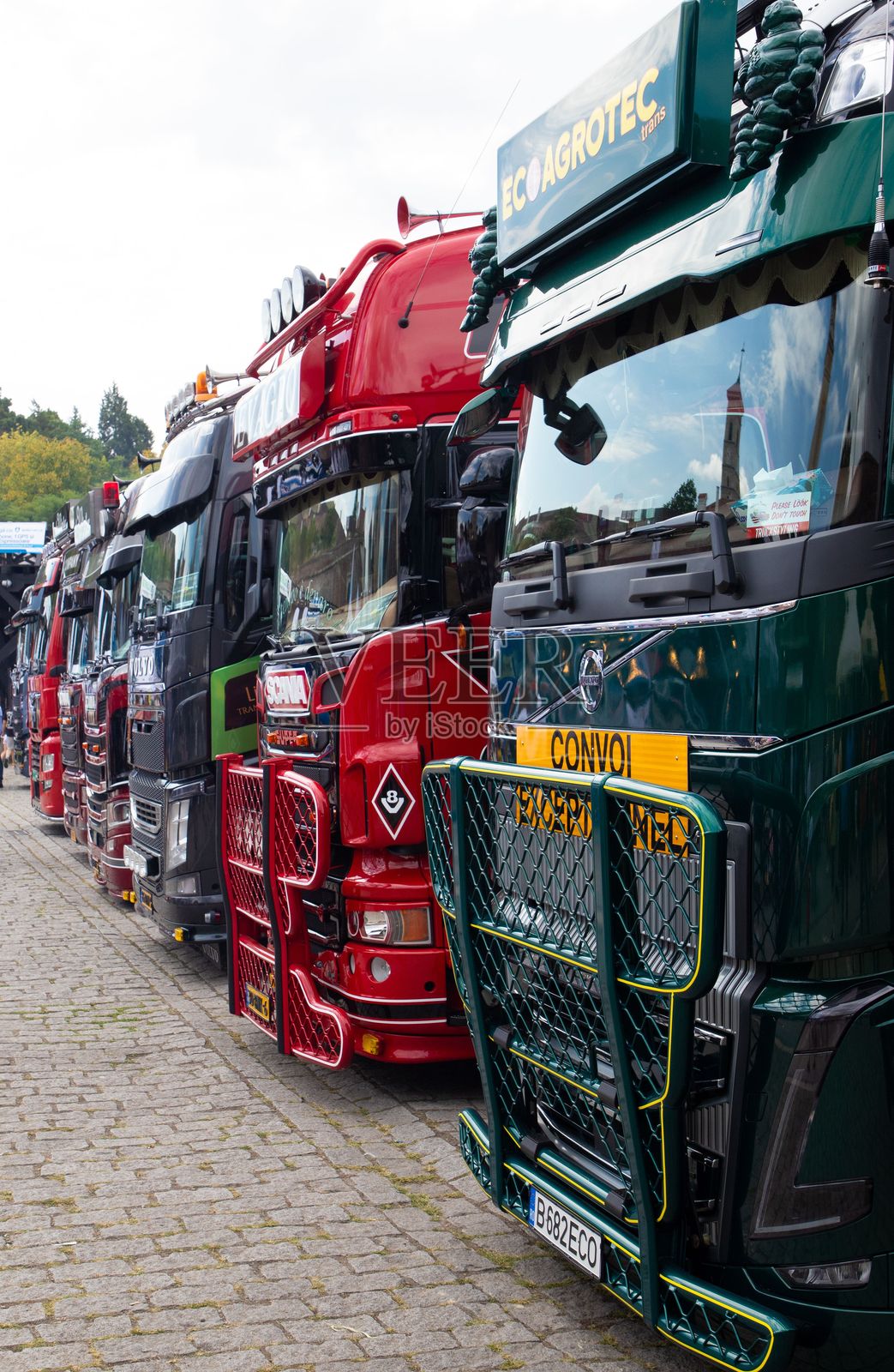 在白天的卡车调音艺术节上，停放在鹅卵石街道上的一排卡车照片摄影图片