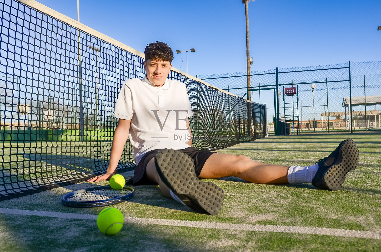 年轻的网球运动员在阳光明媚的日子里训练后休息照片摄影图片