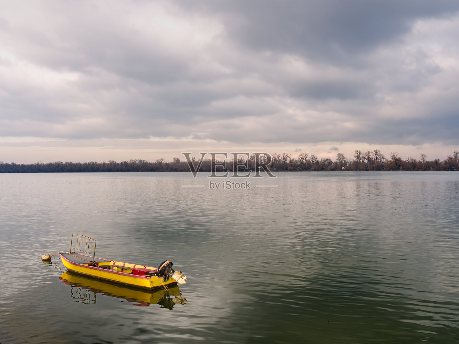 平静的多瑙河上漂浮着一只黄色的小船，天空中布满了云朵。照片摄影图片