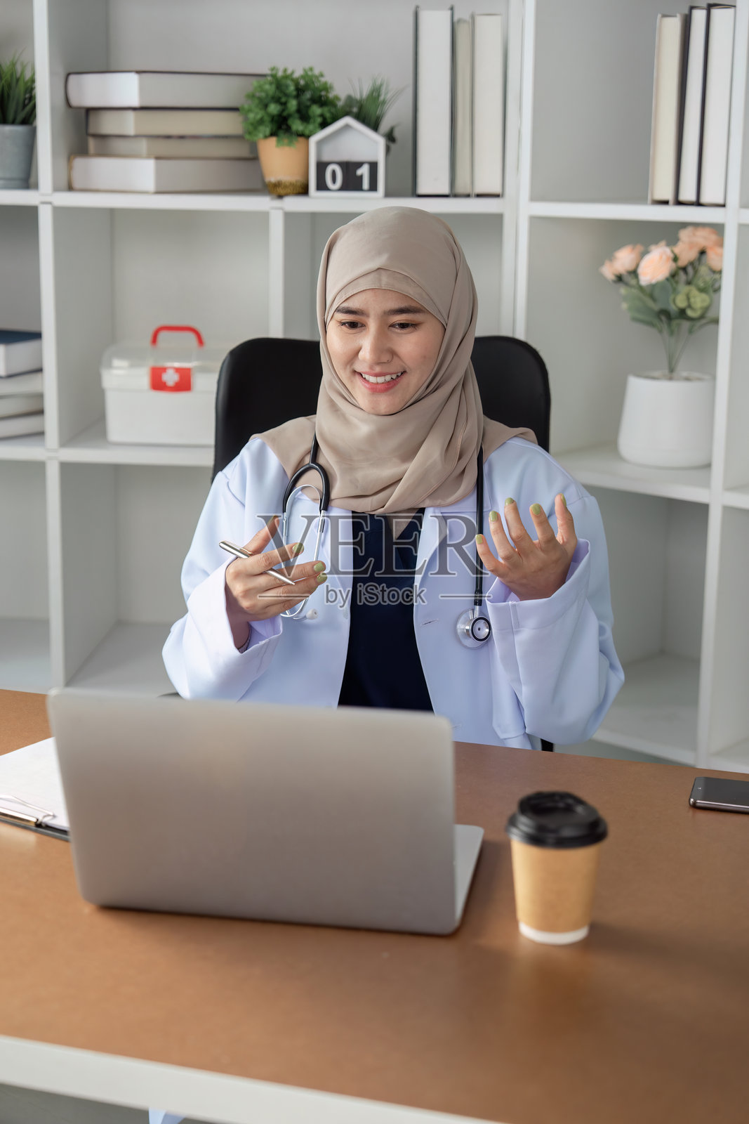 一位积极参与的穆斯林女性医生正在进行虚拟咨询，促进患者互动和医疗包容性。照片摄影图片