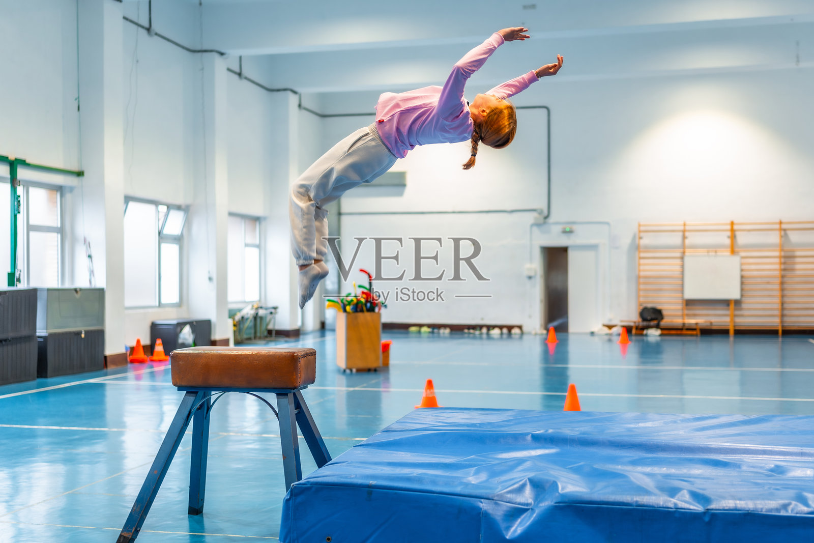 年轻女孩在学校体育馆做体操跳跃照片摄影图片