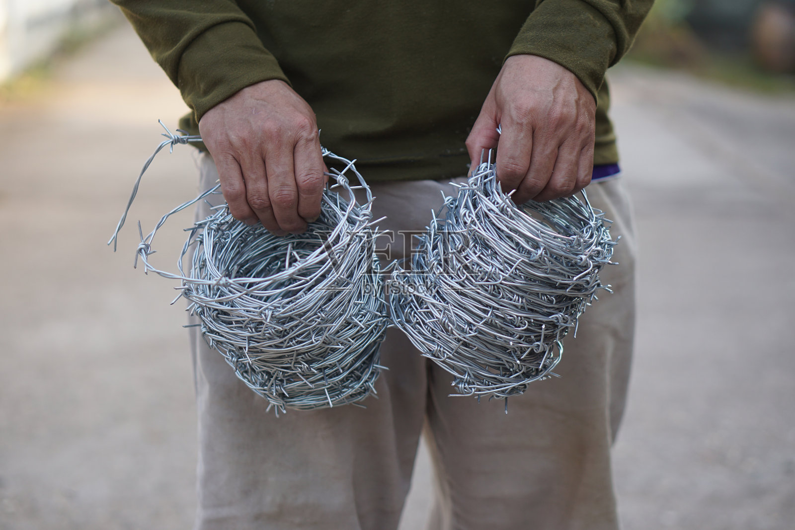 特写工人手握铁丝网卷。概念，建筑工具。铁丝网用于制作围栏，保护财产，划定区域边界。照片摄影图片