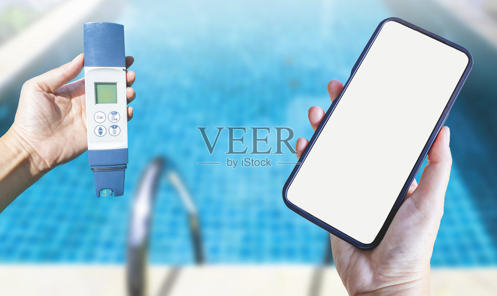 女孩手中拿着数字水质测试仪和智能手机，背景是模糊的游泳池。照片摄影图片