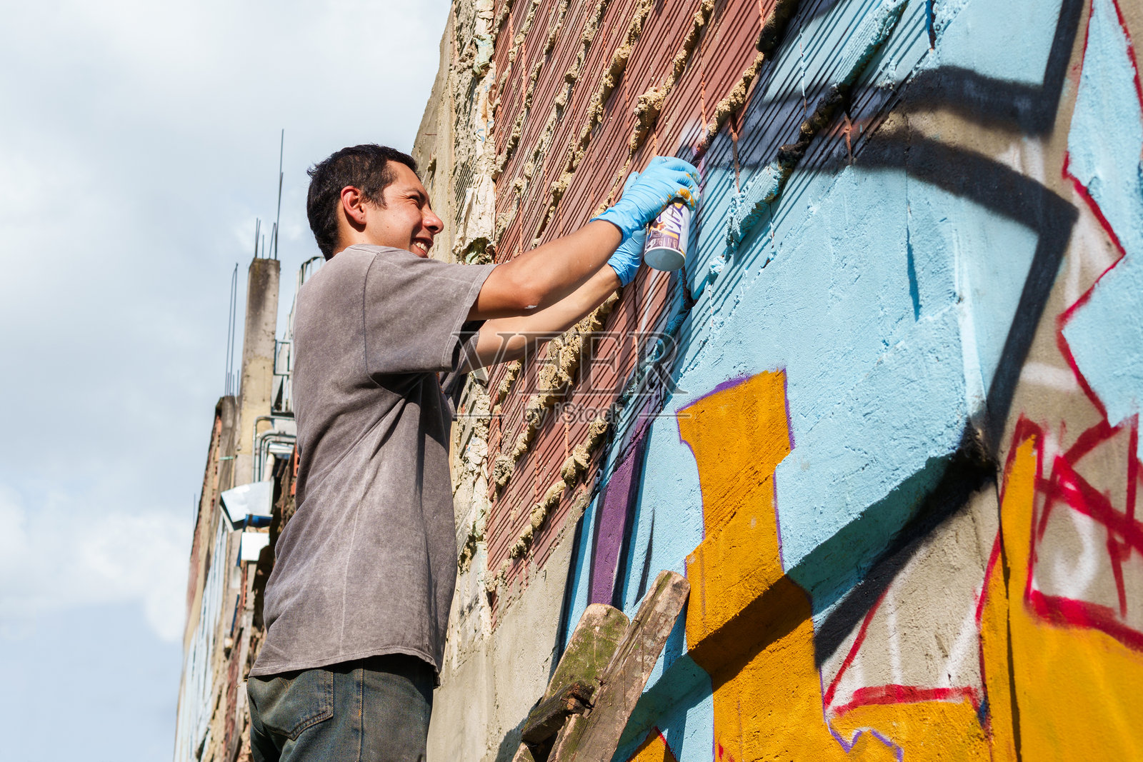 一个男人正在给墙壁喷涂涂鸦照片摄影图片
