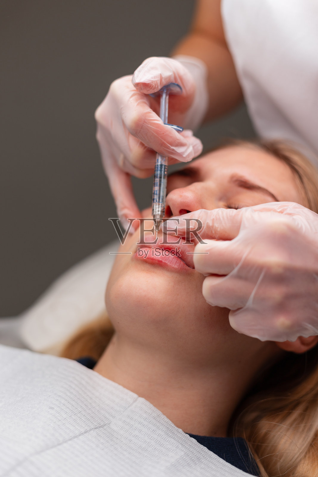 专业美容师在美容诊所进行美容程序。使用填充剂注射进行唇部增厚和修正。照片摄影图片