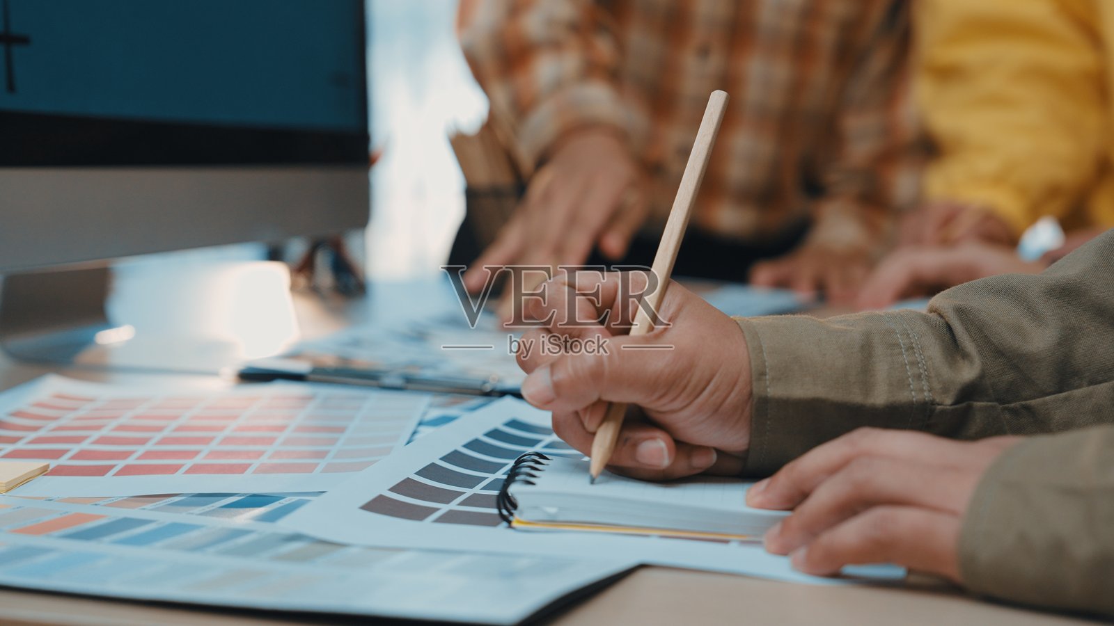 在创意工作空间中，手部参与颜色选择和设计规划，色卡和数字显示器成为焦点照片摄影图片