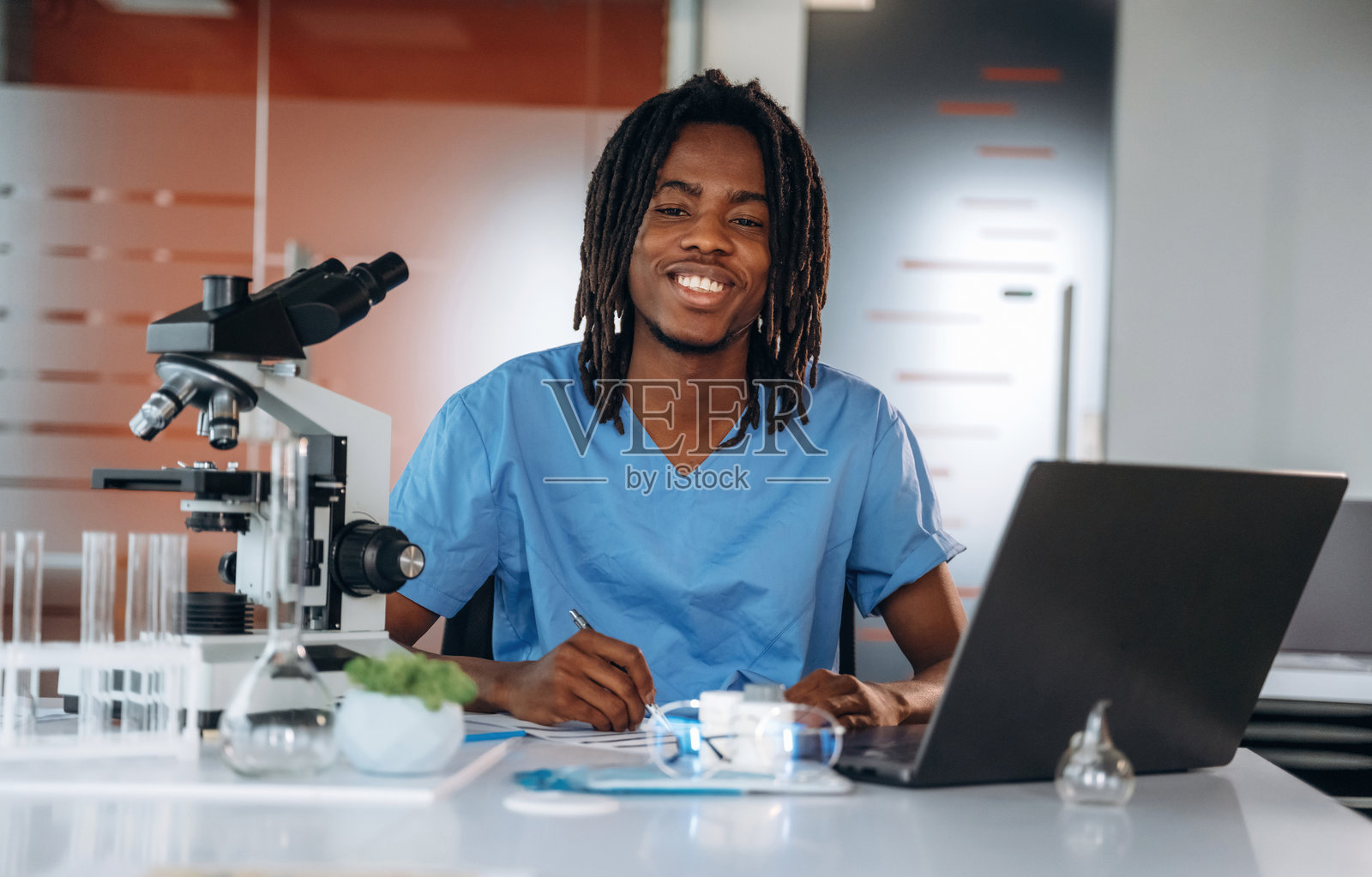 桌子上的显微镜。黑人医生在办公室里。照片摄影图片