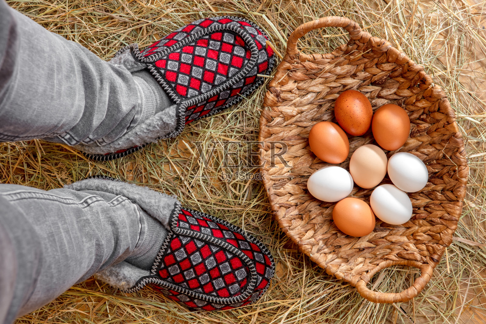 新鲜鸡蛋放在干草里的篮子里，旁边是一个人的腿照片摄影图片