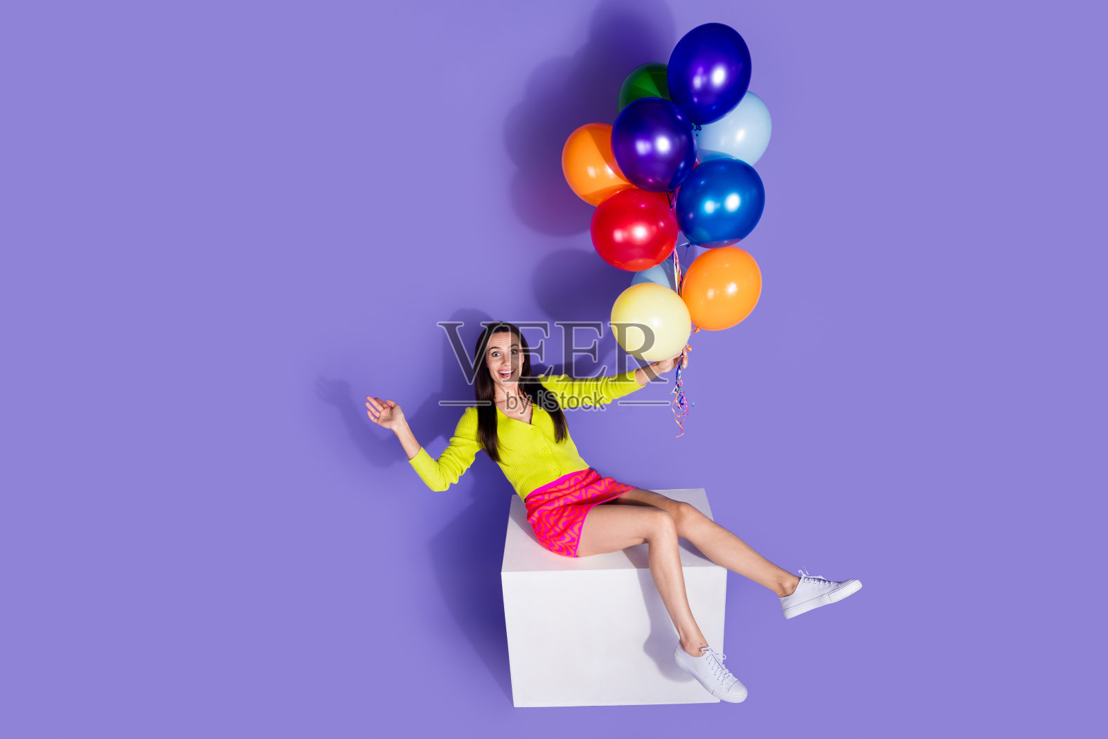 穿着时尚衣服的美丽女孩手持氦气球，背景为紫色空白空间照片摄影图片