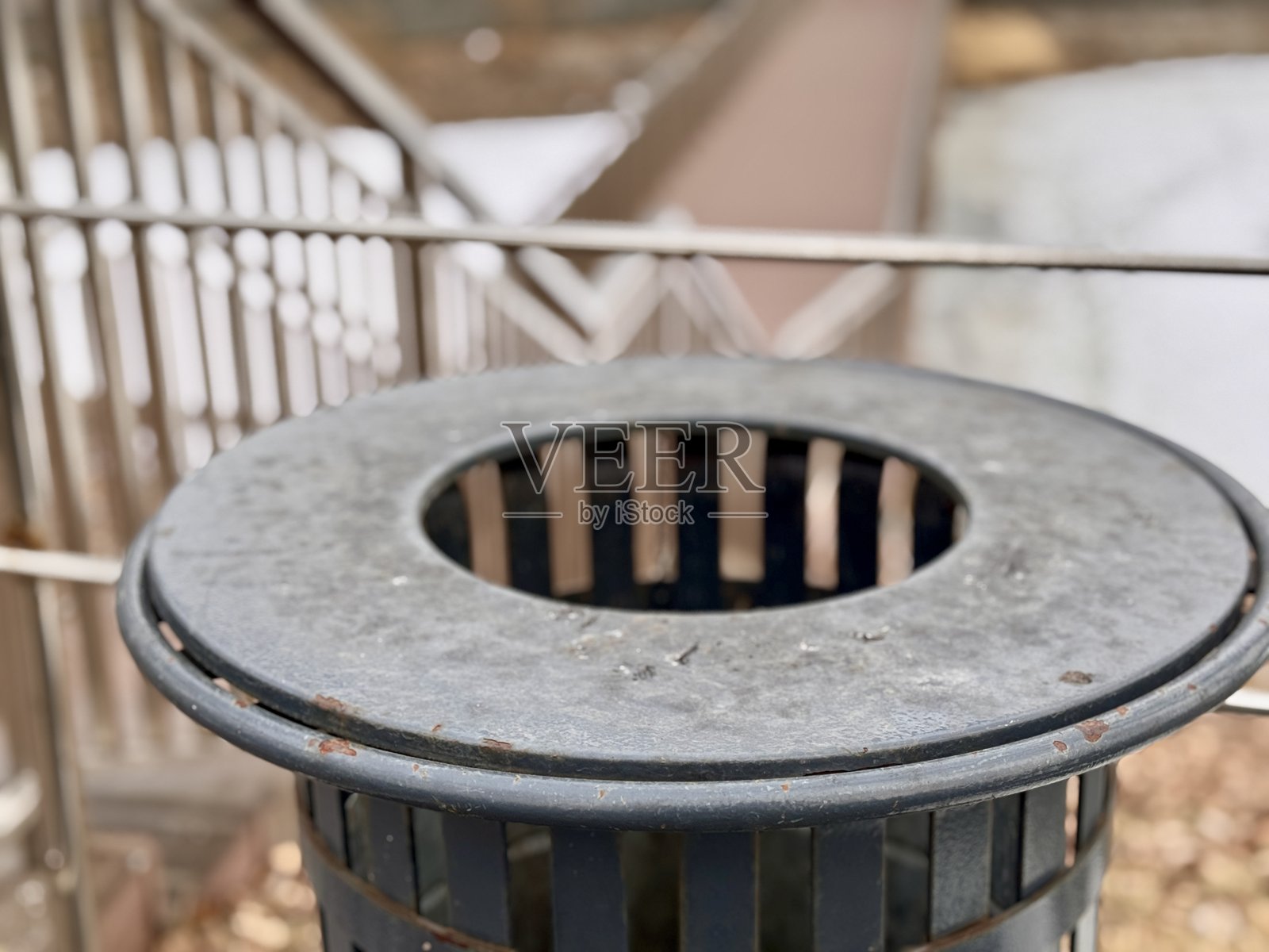 一个金属垃圾桶位于户外城市环境中，周围覆盖着新鲜的积雪。公共空间中的城市垃圾桶对社区的清洁和垃圾处理效率至关重要。照片摄影图片