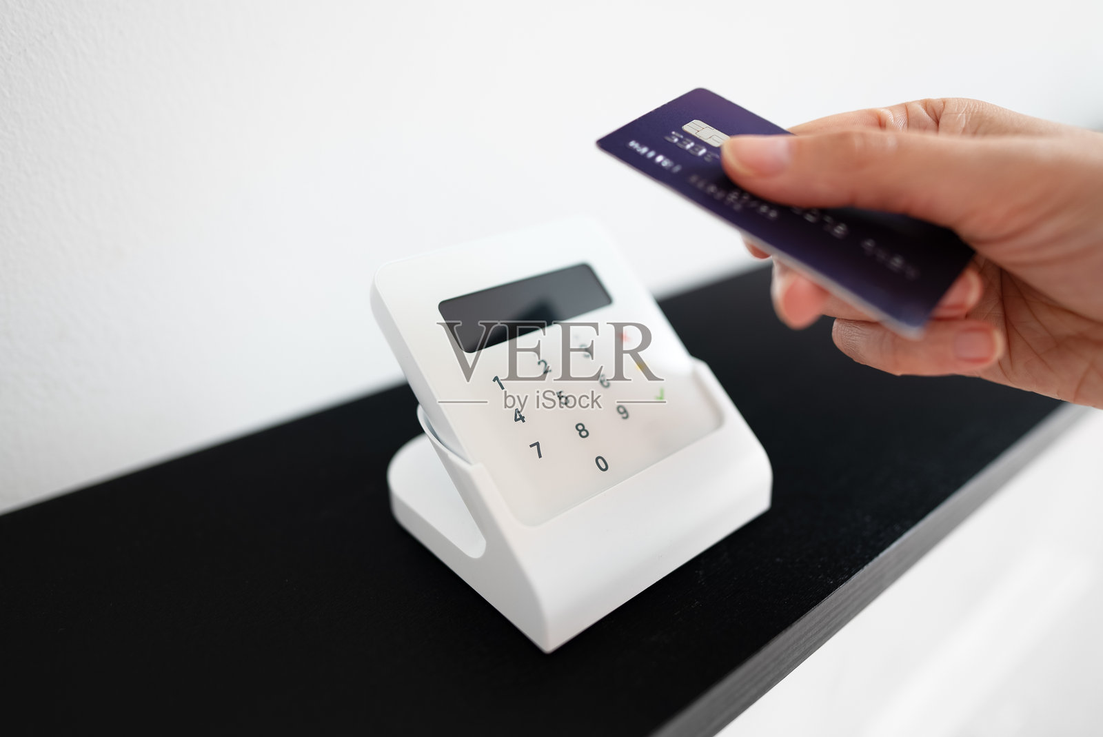 女性的手在无线终端上使用卡片进行非接触式支付。照片摄影图片