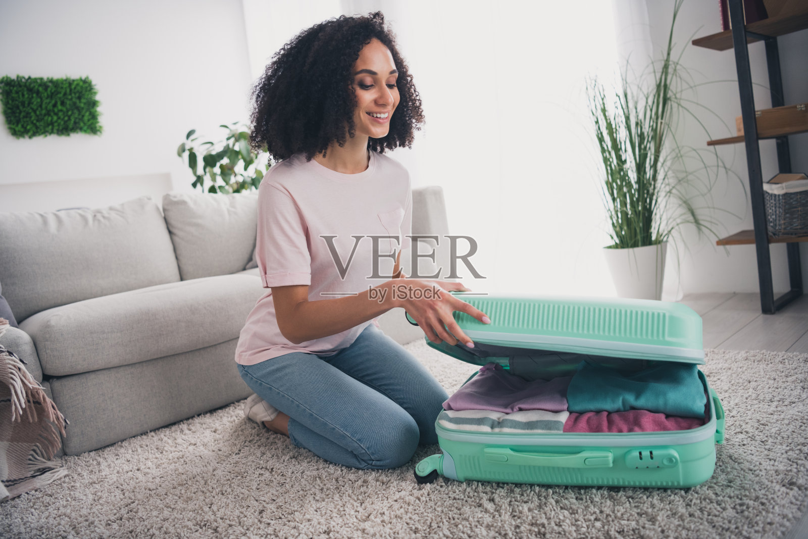 可爱迷人的小女孩坐在地板上，准备周末旅行的衣物，室内环境。照片摄影图片