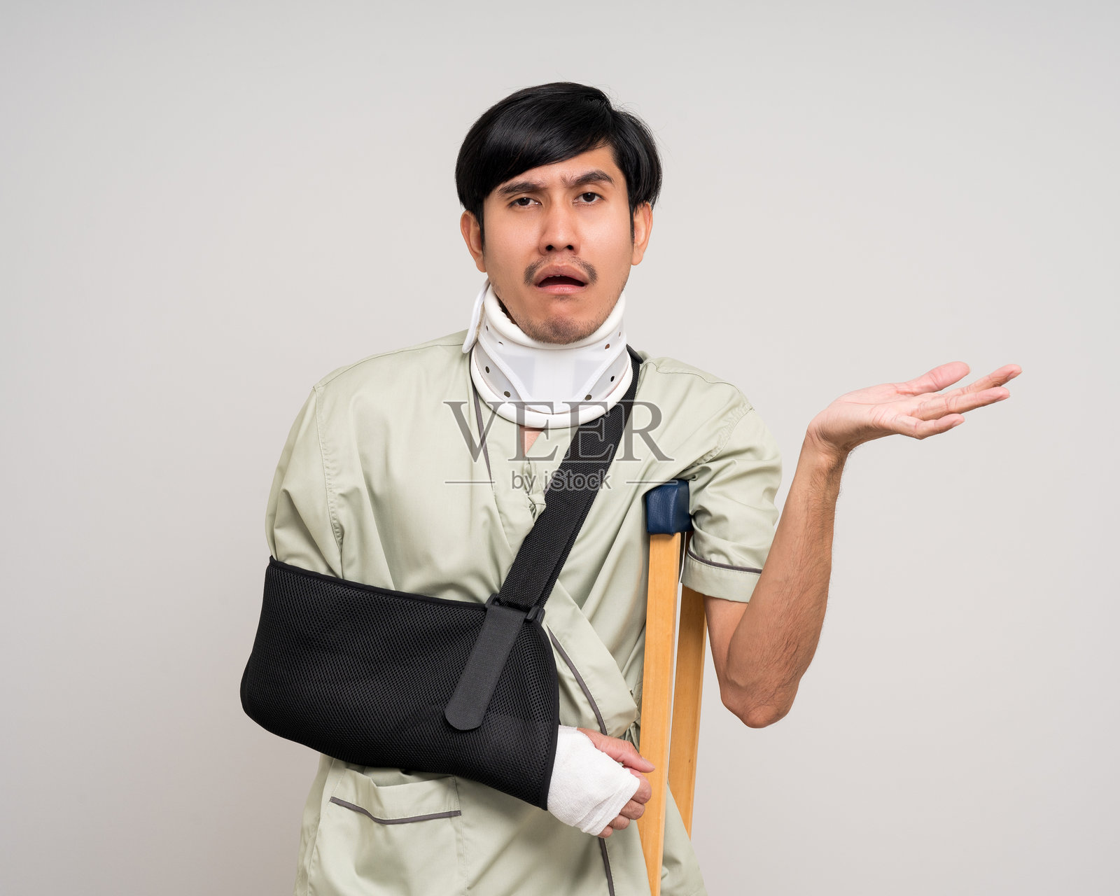 痛苦的抑郁男子。手臂骨折。亚洲男子正在接受石膏绷带固定。男性患者在事故受伤后佩戴支撑臂的吊带。人寿保险和意外事故。照片摄影图片