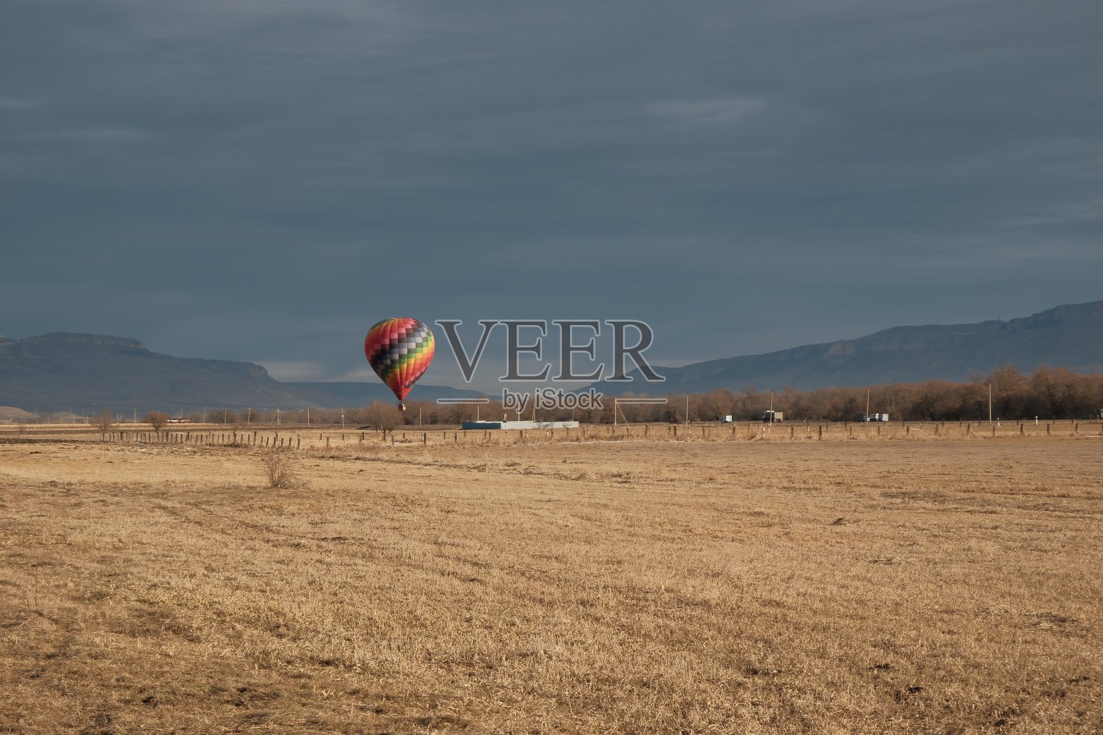 热气球在割过的田野上升入空中照片摄影图片
