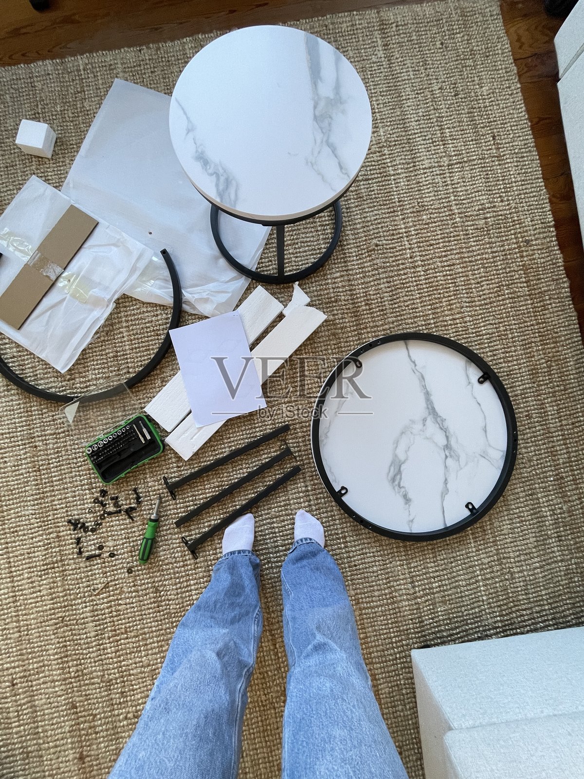 女性组装家具的视角，俯视地毯上的零件照片摄影图片