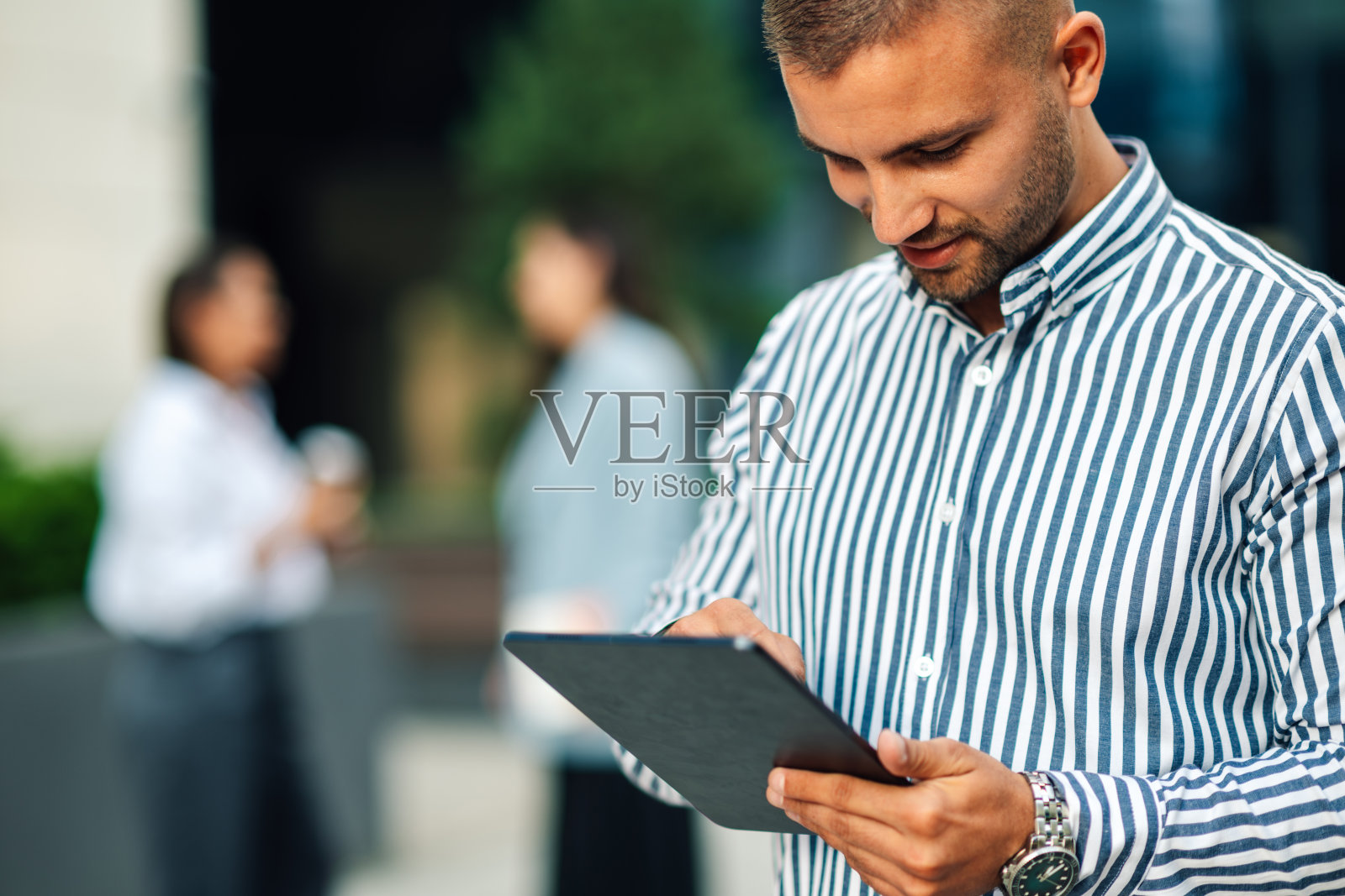 商人在办公楼外使用数字平板电脑照片摄影图片