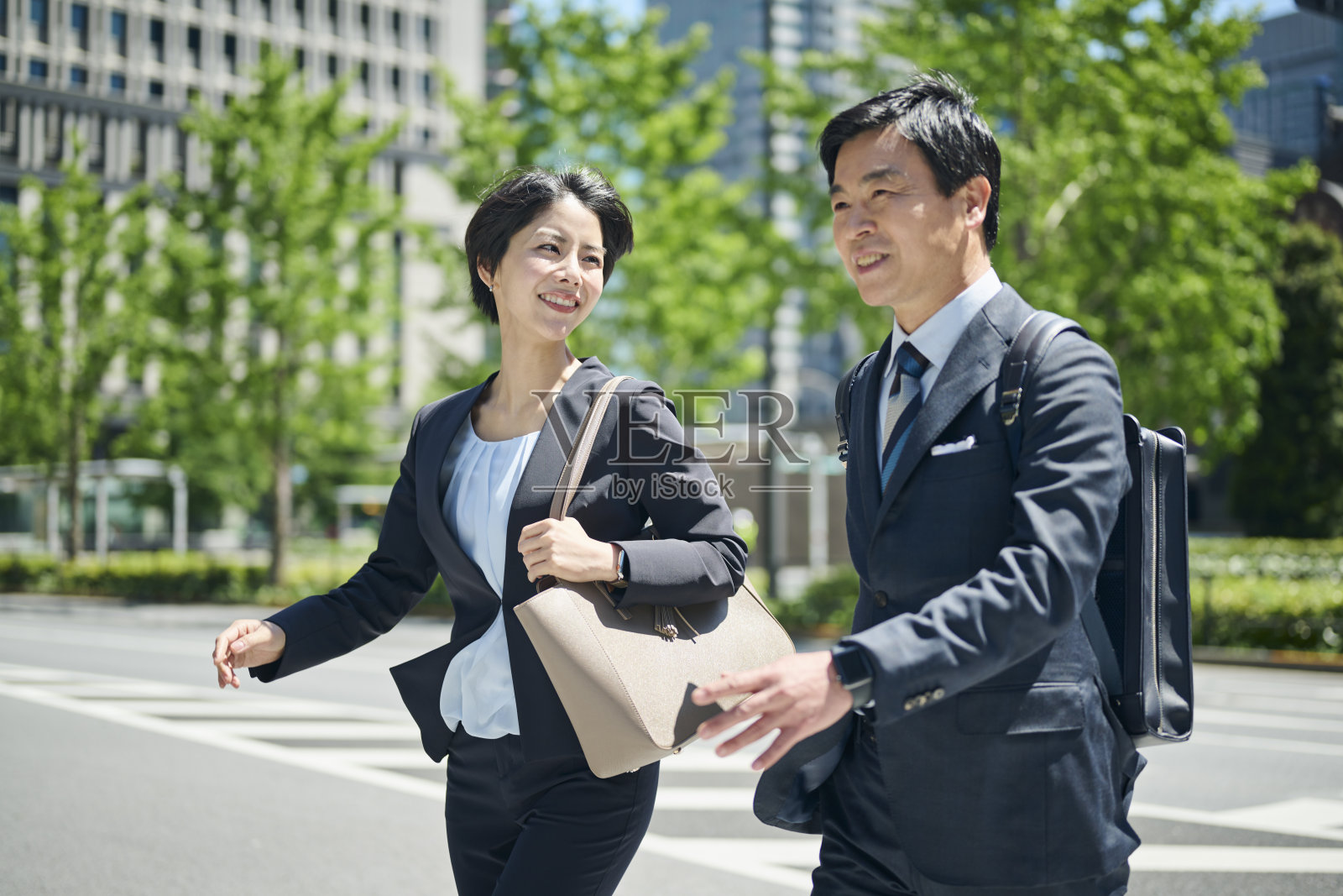 一位50多岁的男性办公室工作人员和一位30多岁的女性办公室工作人员在商业区散步照片摄影图片