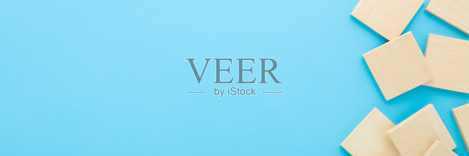 浅蓝色桌面上的木质拼图方块。柔和的色彩。特写。儿童发展桌面游戏。宽幅横幅。文本空白处。俯视图。照片摄影图片