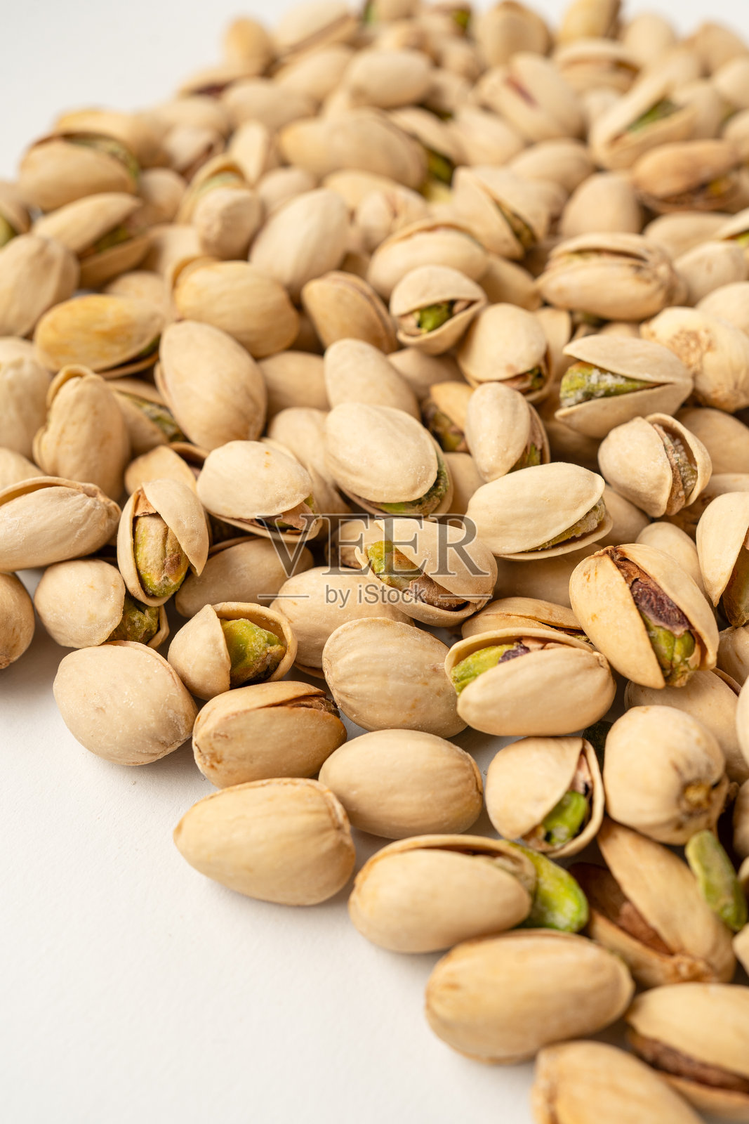 大量盐焗开心果在白色背景上，孤立，俯视图，酥脆的烤坚果，美味又营养的零食，健康有机食品，高蛋白素食成分，带壳开心果照片摄影图片