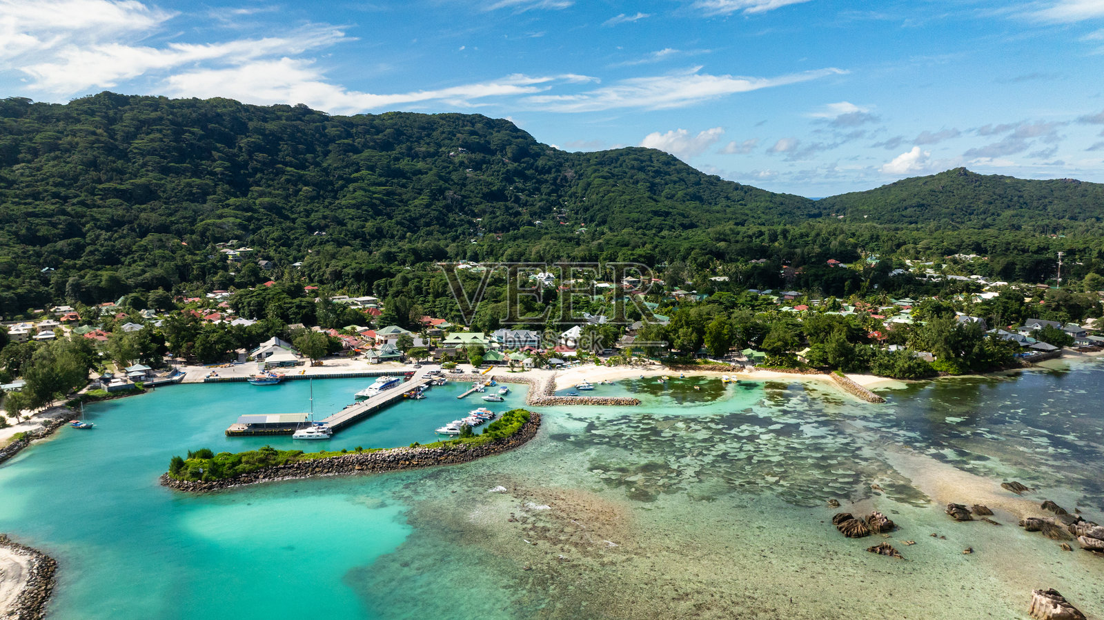 被郁郁葱葱的山丘环绕的港口小镇。照片摄影图片