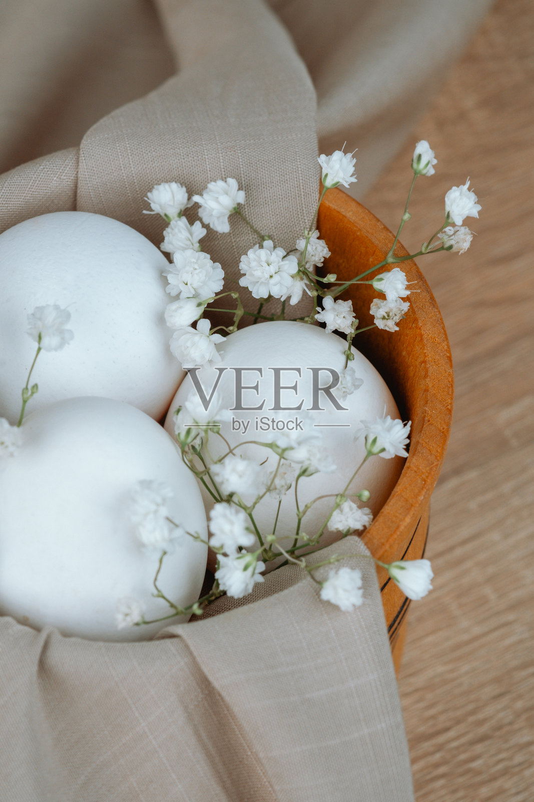 白色鸡蛋与婴儿花环在木碗中。复活节背景。照片摄影图片