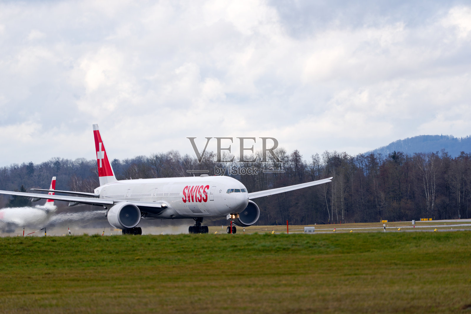 瑞士航空的波音777-300ER客机HB-JNL在瑞士苏黎世克洛滕机场的雨天冬季起飞的美丽景色。照片摄影图片