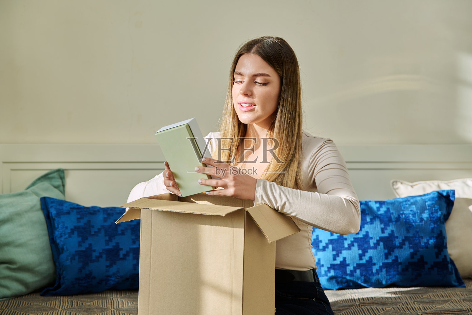 年轻女性正在拆开纸箱，查看新的化妆品和香水。照片摄影图片