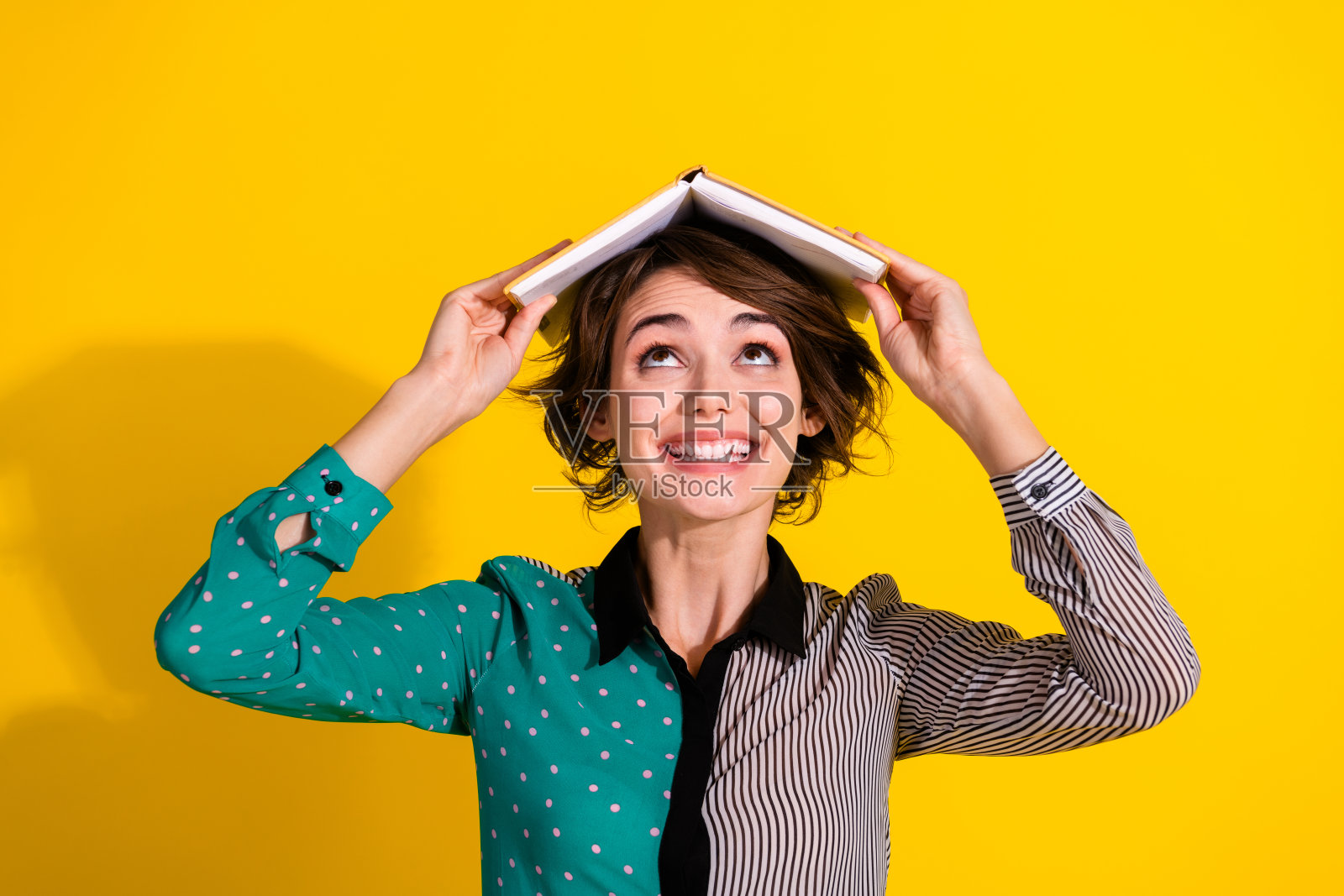 迷人可爱的女孩穿着时尚的衣服，手持书本，背景为空白的黄色。照片摄影图片