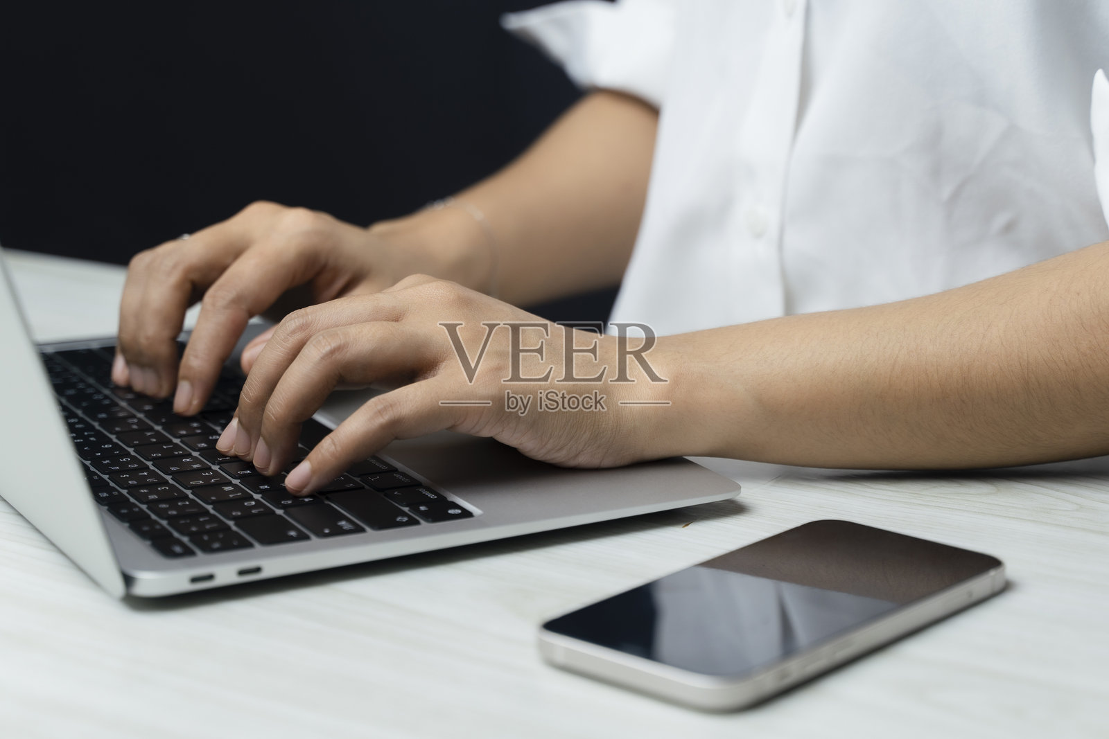 年轻商人在办公室里用手在笔记本电脑上打字的特写镜头。照片摄影图片