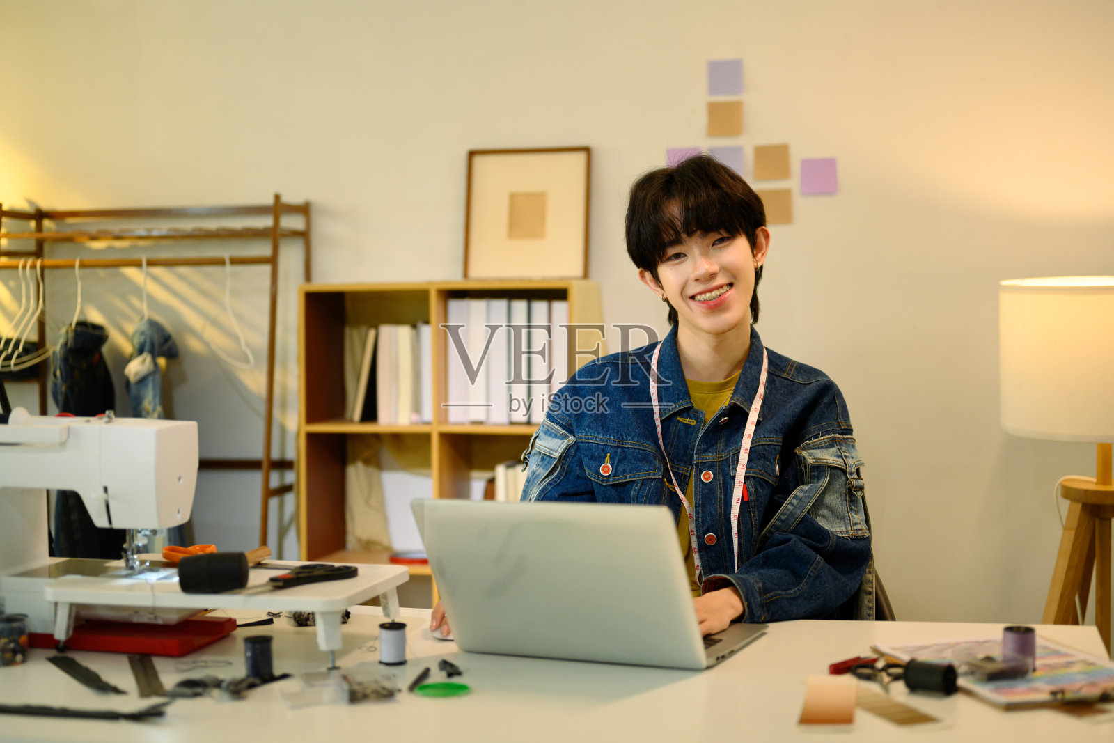 微笑的时尚设计师在工作室里使用笔记本电脑照片摄影图片