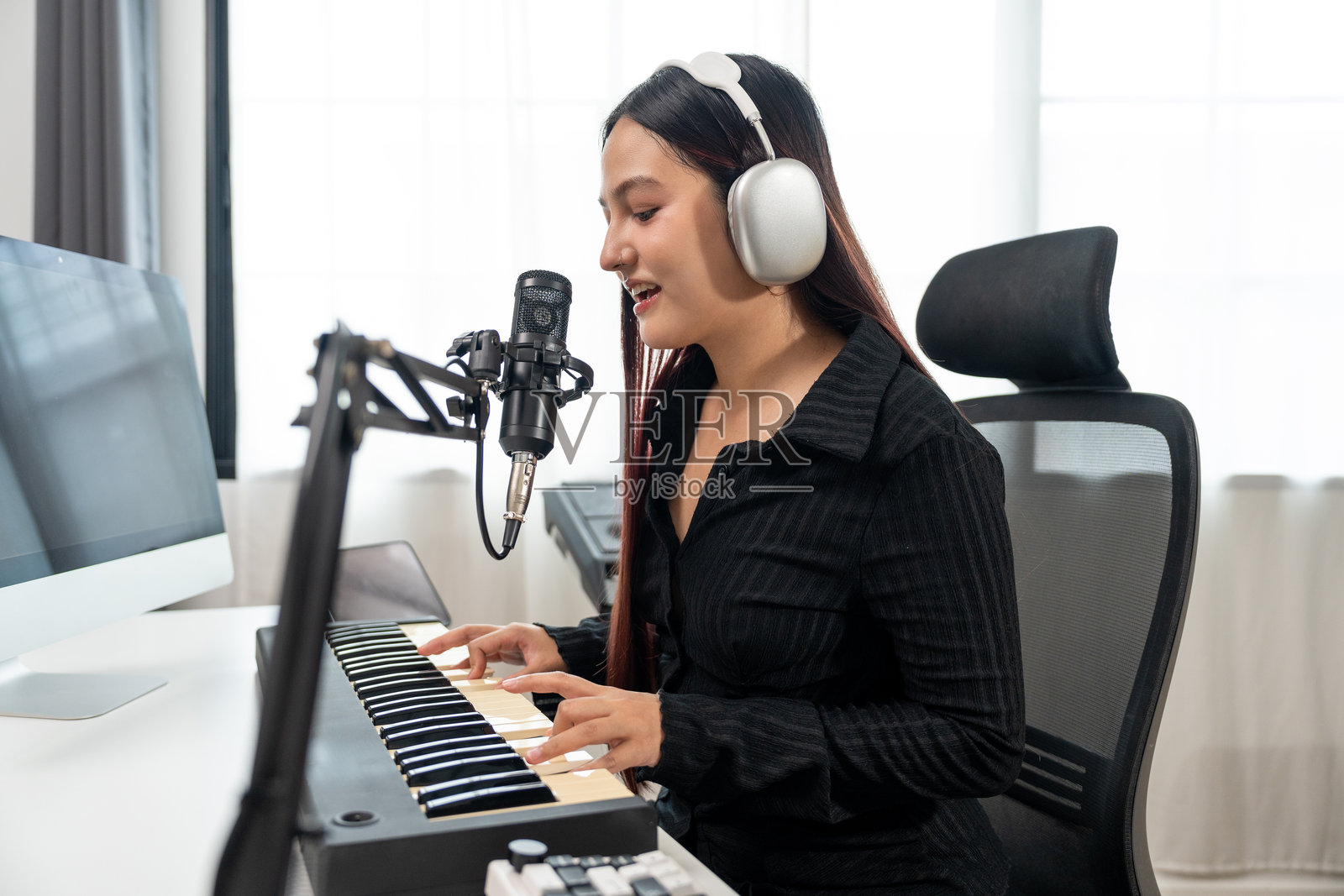 专业音乐人使用电容麦克风和平板电脑进行音乐混音和母带制作。音乐作曲家女性在数字录音家庭工作室中用吉他和钢琴键盘创作歌曲。照片摄影图片