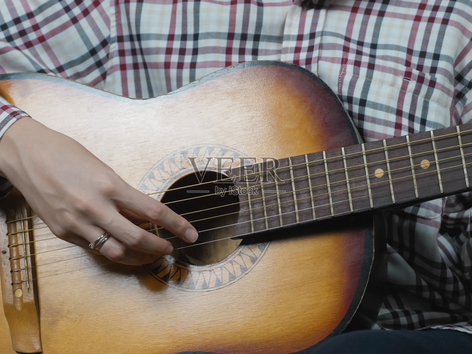 特写镜头展示了一位音乐家熟练地弹奏着原声吉他，热情地拨动琴弦，创造出充满情感和艺术感的美妙旋律。照片摄影图片