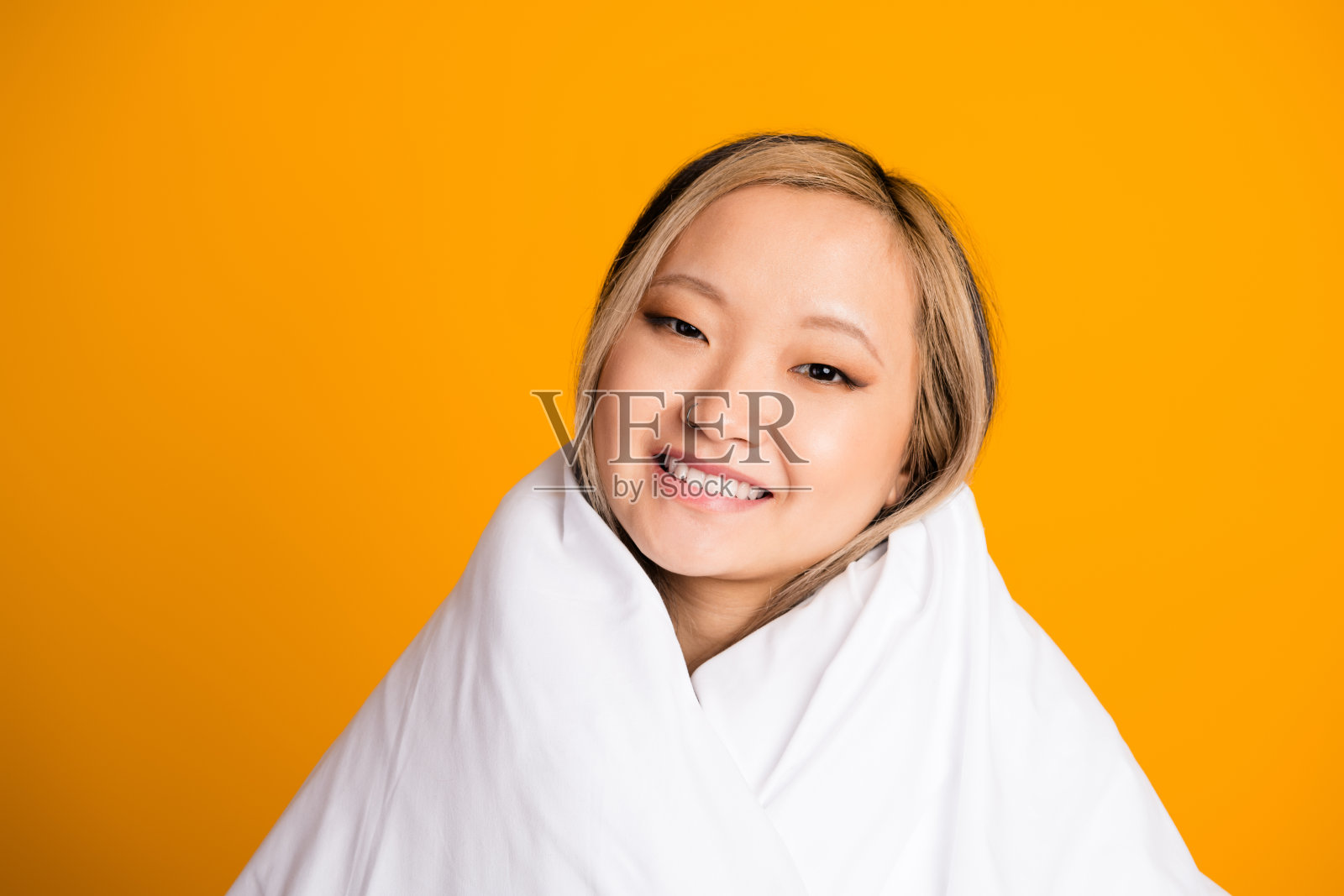 可爱的女人裹着温暖的毛毯，享受在黄色背景下的休息时光照片摄影图片