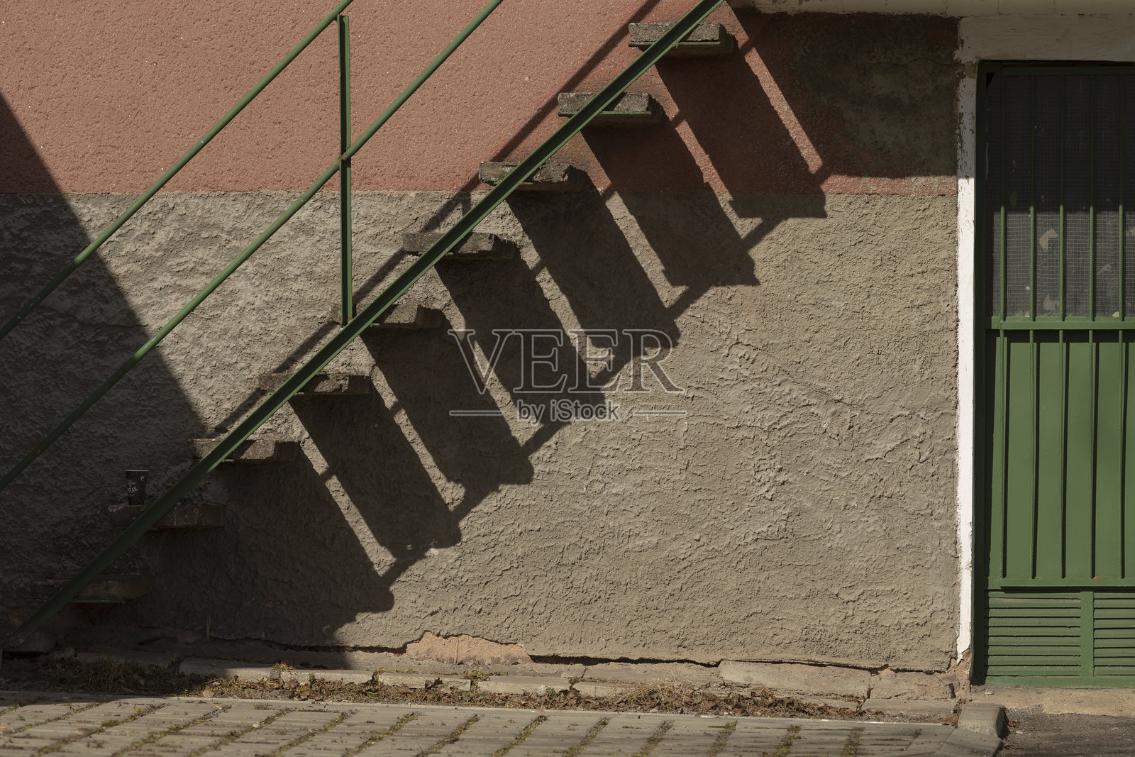 一座生机勃勃的绿色楼梯在建筑物侧面投下深深的阴影照片摄影图片