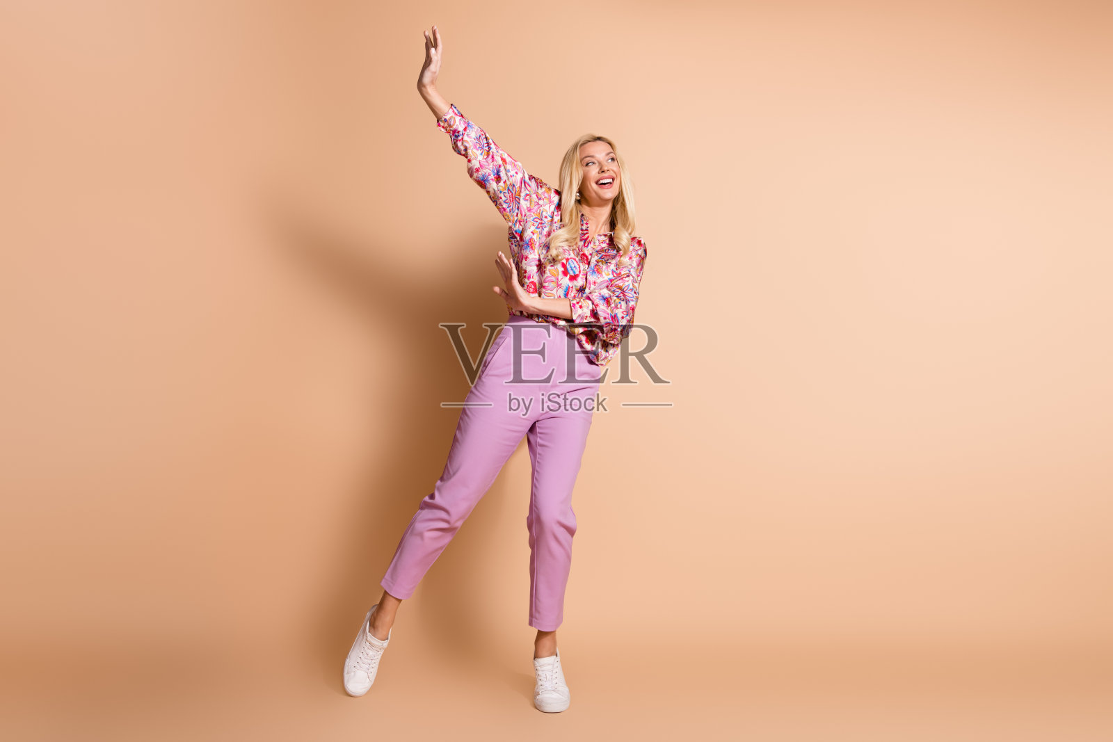 穿着衬衫的美丽女士在米色背景下舞动，展现出空旷的空间感。照片摄影图片