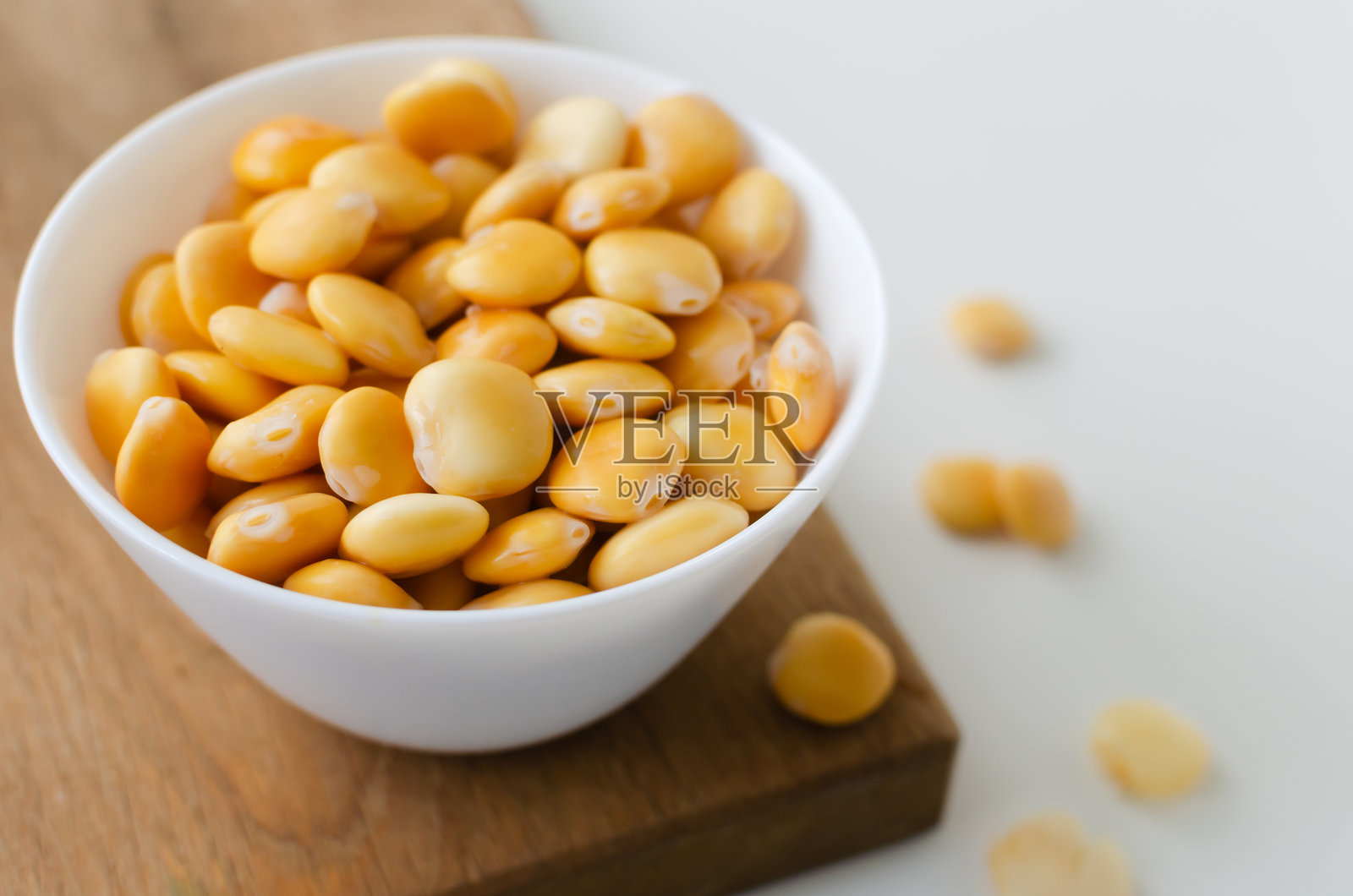 白色桌子上的切菜板上放着一个装有卢宾豆的白碗。意大利美食。豆类的一种。健康饮食概念。横向构图。选择性焦点。留白空间。照片摄影图片