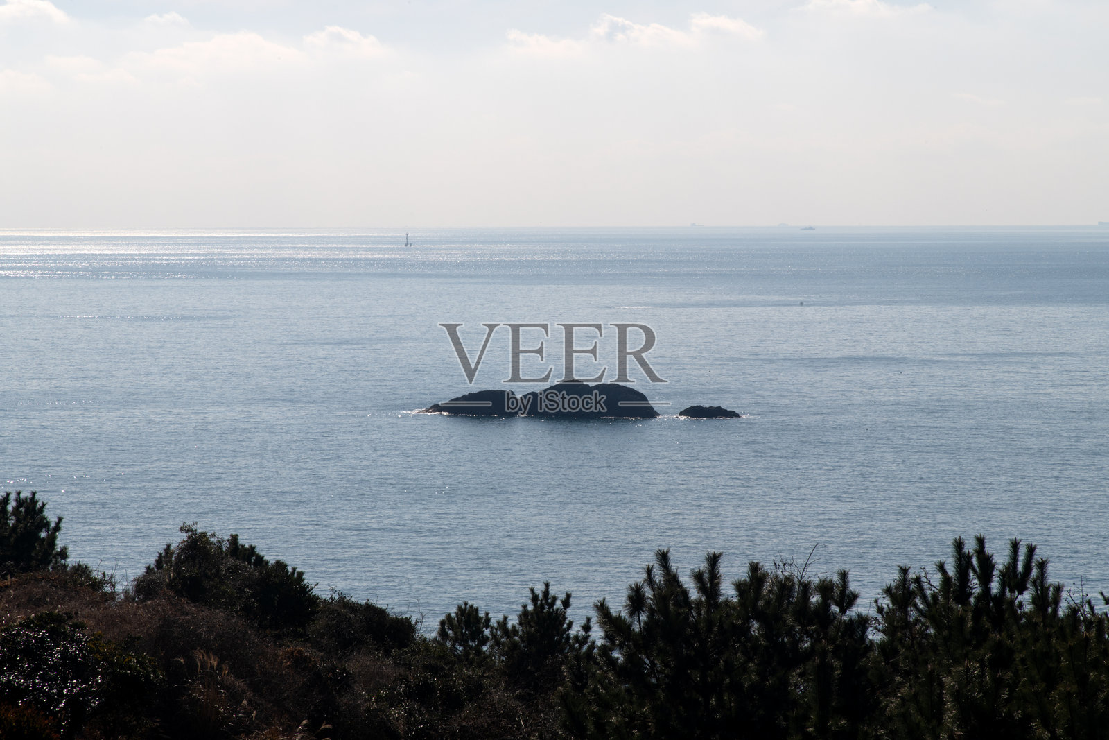 阳光明媚的日子里的岩石与海洋照片摄影图片