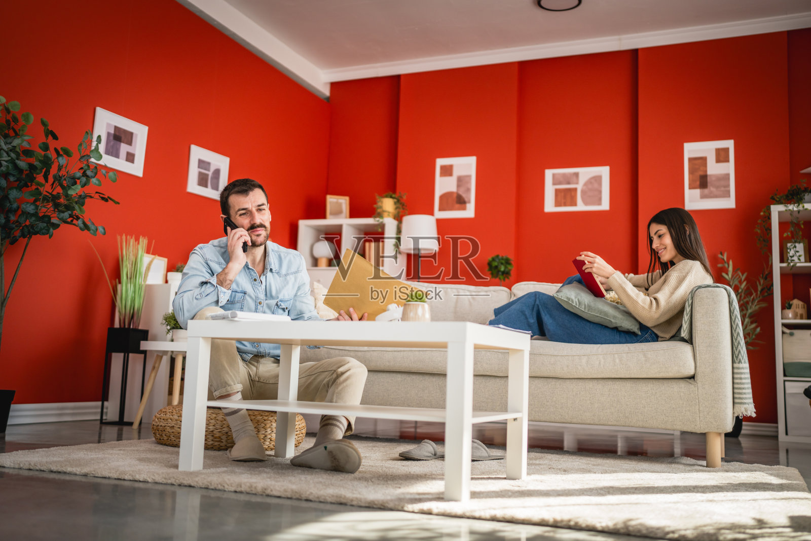 成年男子坐在家里的地板上，打电话。照片摄影图片