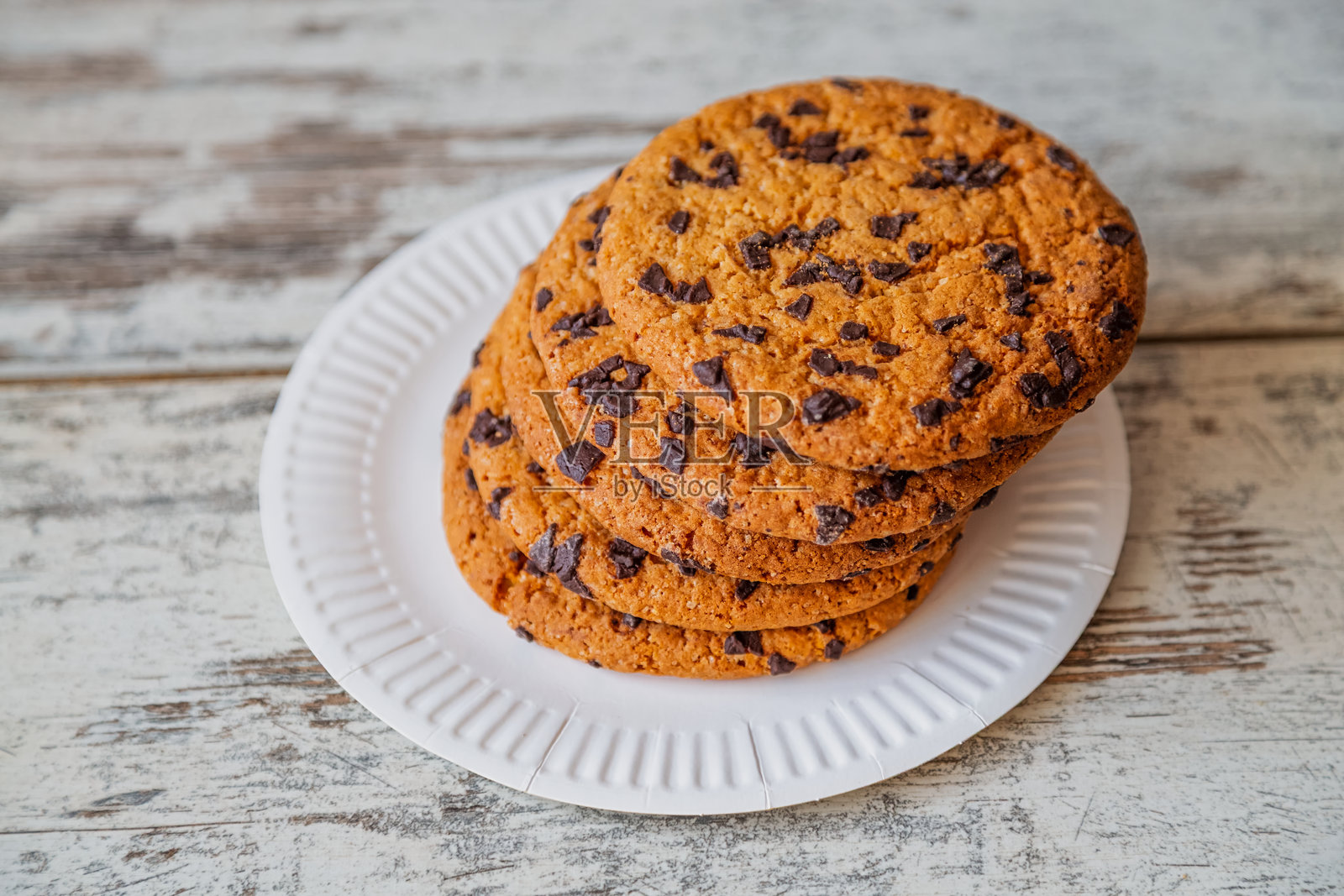 巨大的巧克力饼干，上面有融化的巧克力块，放在一张古老的木桌上——象征着温馨的舒适和烹饪传统。照片摄影图片