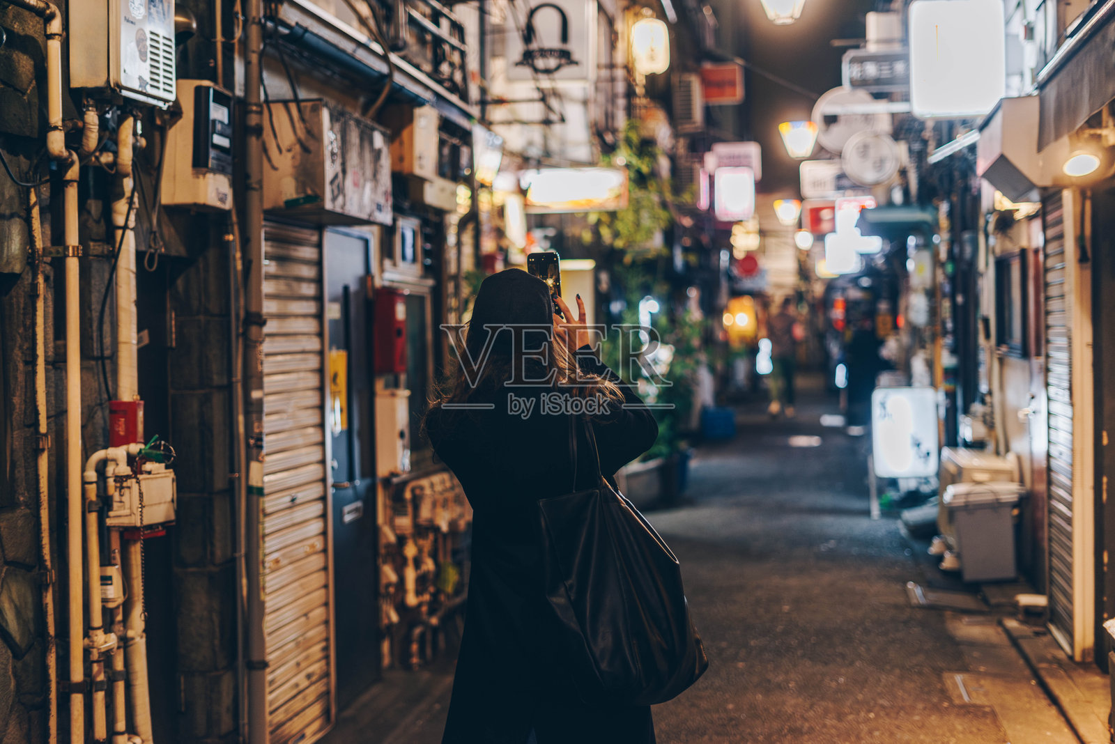 女性游客在东京著名酒吧街拍照照片摄影图片