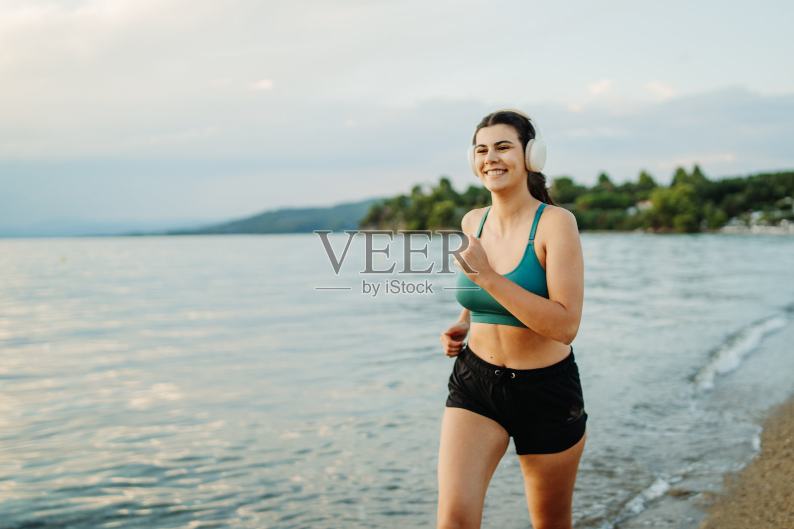 年轻女性在日落时分的海滩上跑步或慢跑照片摄影图片