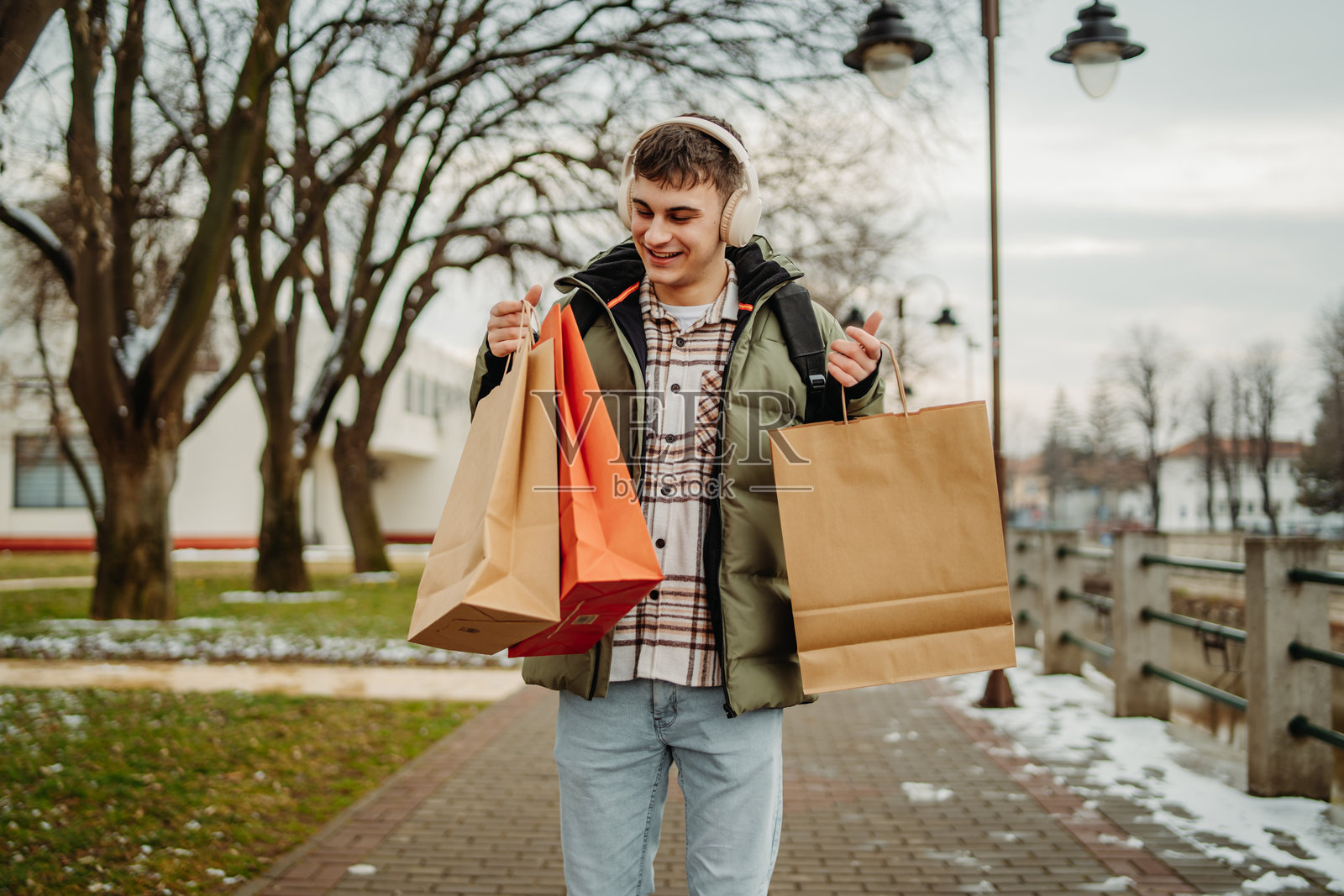年轻男学生微笑着提着购物袋走回家照片摄影图片