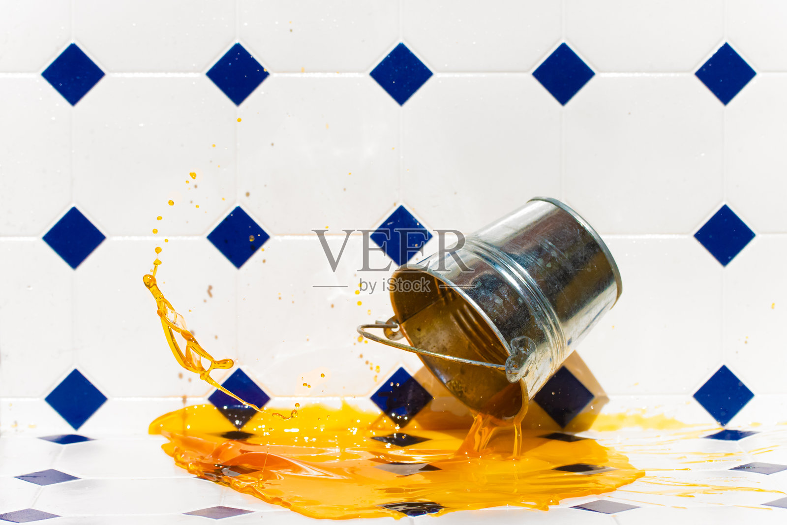 一个金属桶掉到地板上，溅出了彩色液体。照片摄影图片